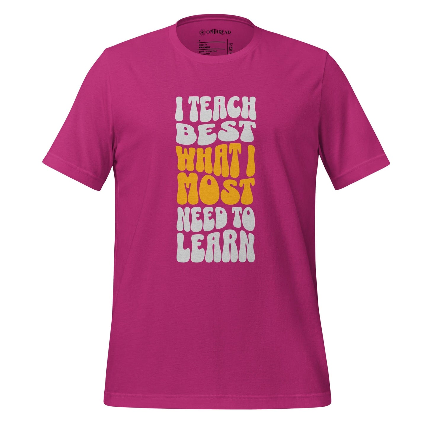 OMTHREAD barbie pink t-shirt with bold white and yellow text reading "I Teach Best What I Most Need to Learn" in a retro-style font.