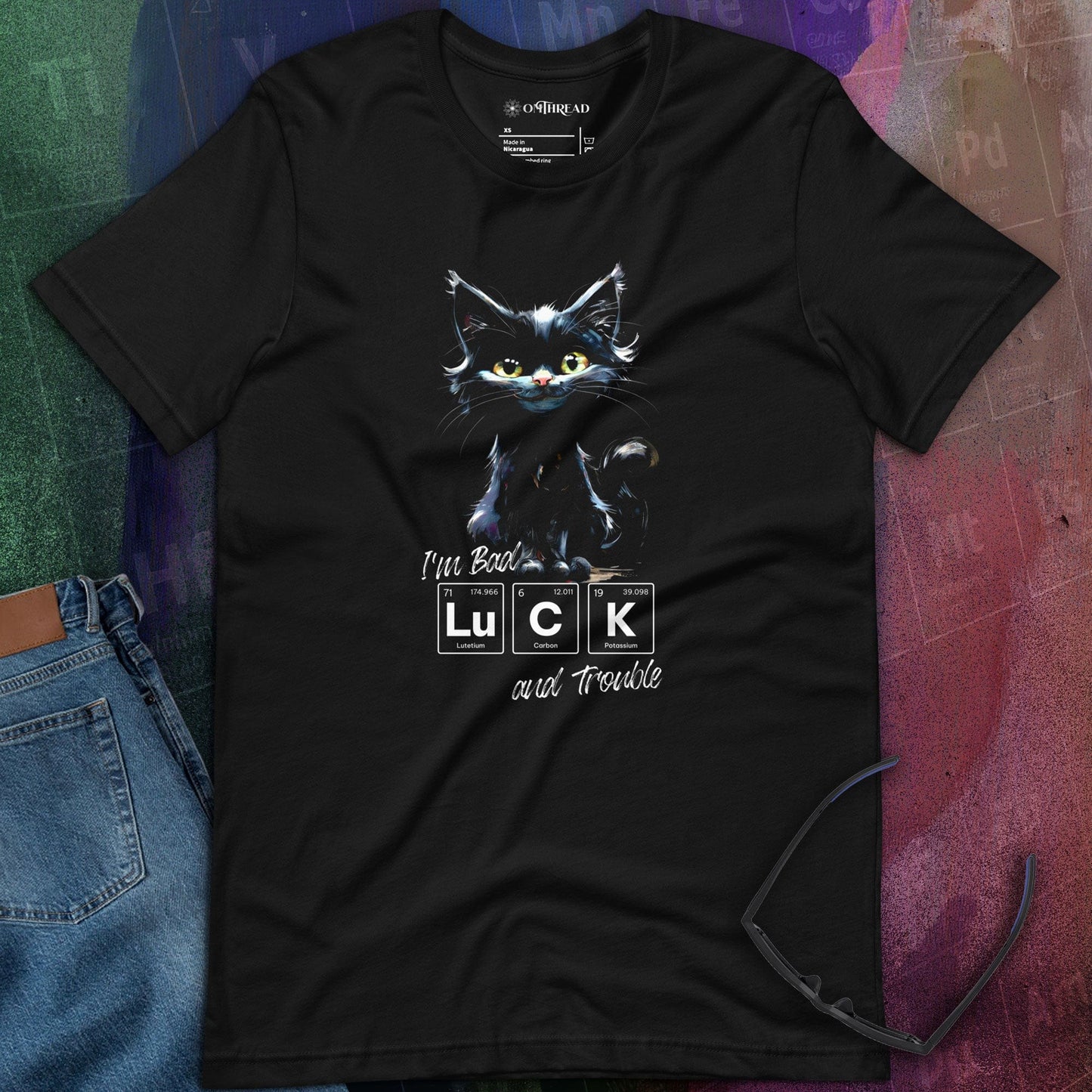 OMThread black t-shirt featuring an illustrated black cat with green eyes, paired with a periodic table-inspired design spelling "LUCK" and handwritten text "I'm Bad Luck and Trouble" below. The design is centered on the shirt