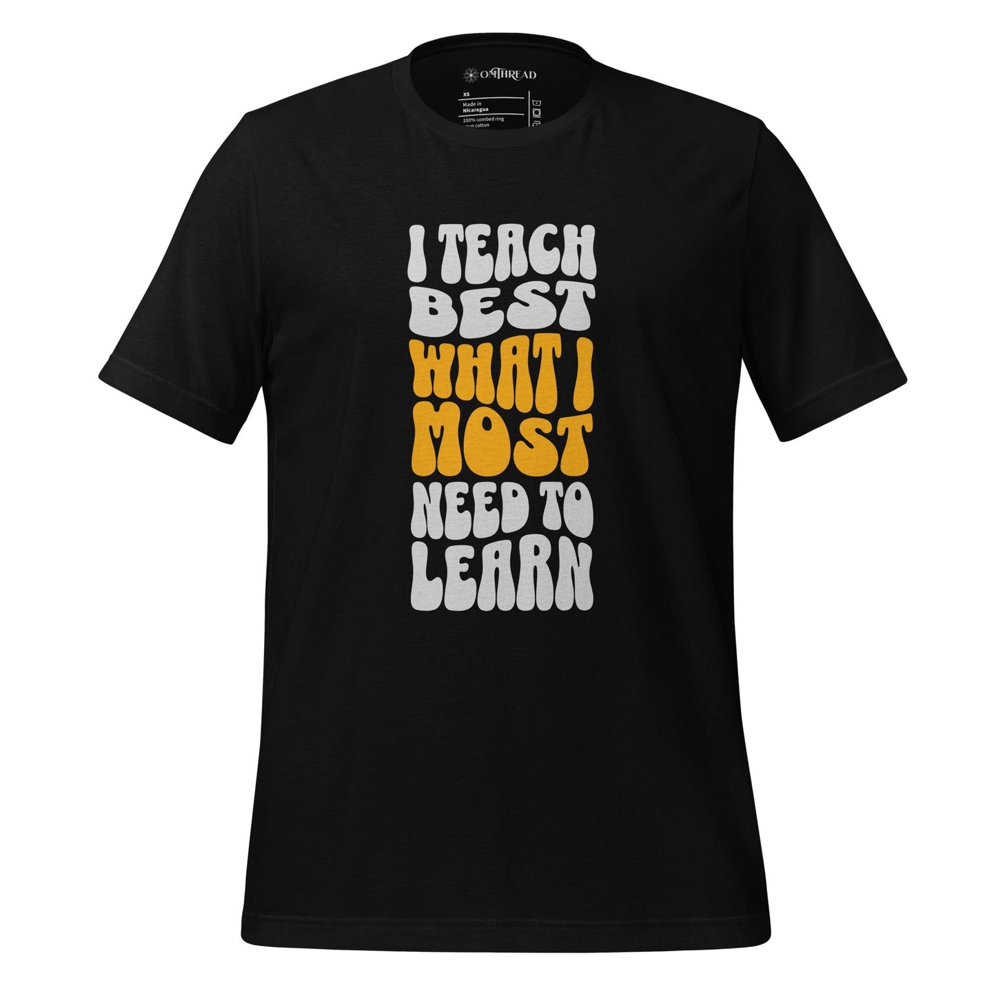 OMTHREAD black t-shirt with bold white and yellow text reading "I Teach Best What I Most Need to Learn" in a retro-style font.