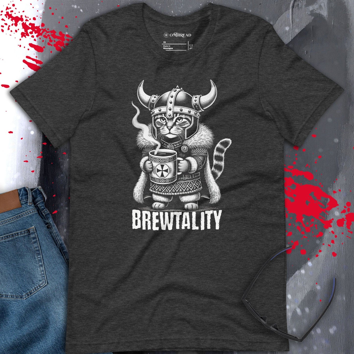 OMTHREAD dark gray t-shirt featuring a Viking cat in a horned helmet, gripping a steaming mug of coffee. The word 'Brewtality' is printed below in bold lettering. The feline wears Nordic-style armor with a fur cape.