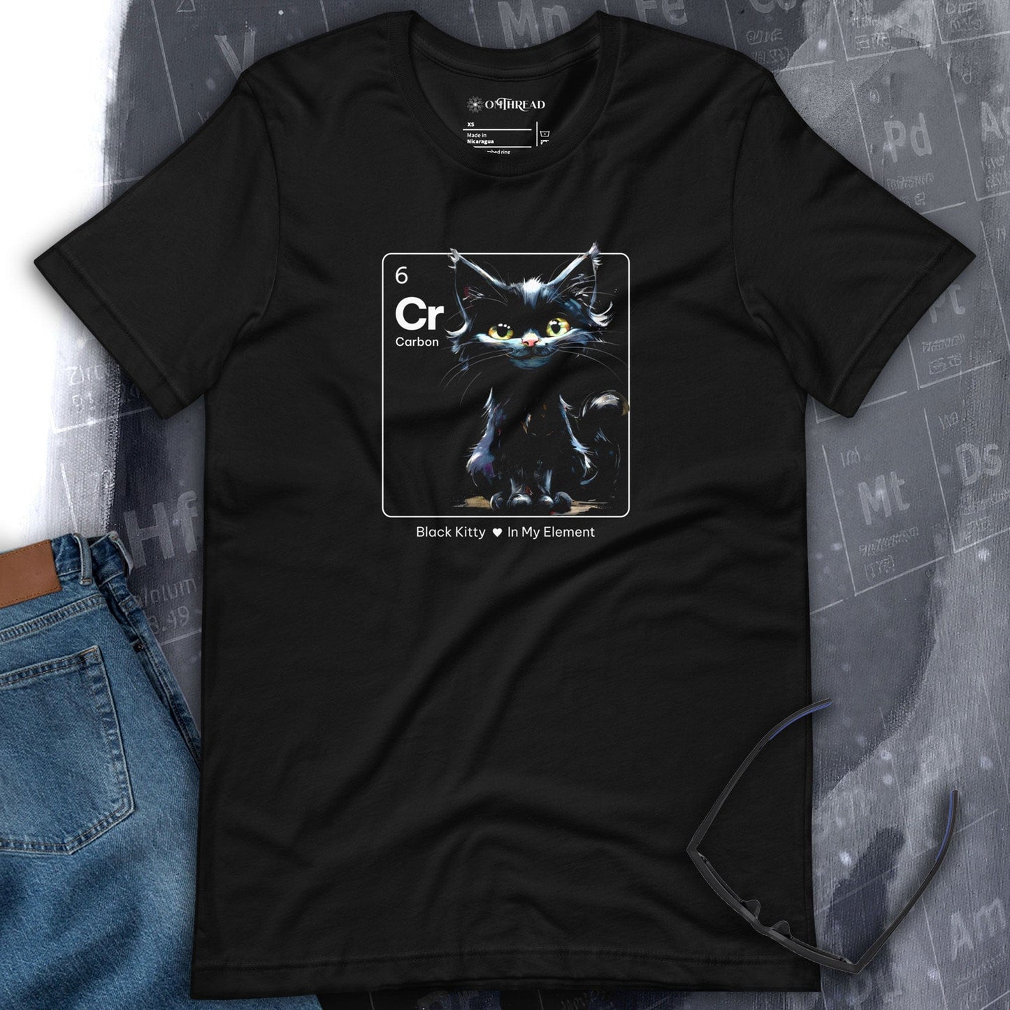 OMThread black t-shirt featuring a black cat illustration inside a periodic table element design labeled "Cr" for Carbon. The cat has piercing eyes and a sleek, mystical appearance. Below the image, the text reads "Black Kitty In My Element."