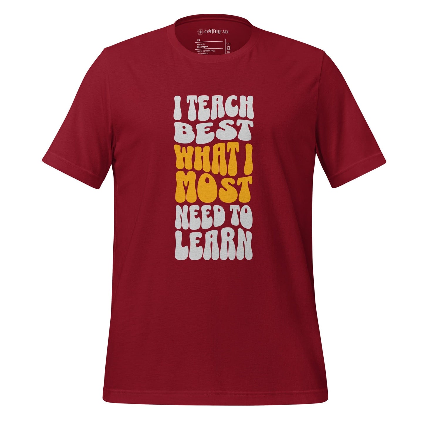 OMTHREAD red t-shirt with bold white and yellow text reading "I Teach Best What I Most Need to Learn" in a retro-style font.