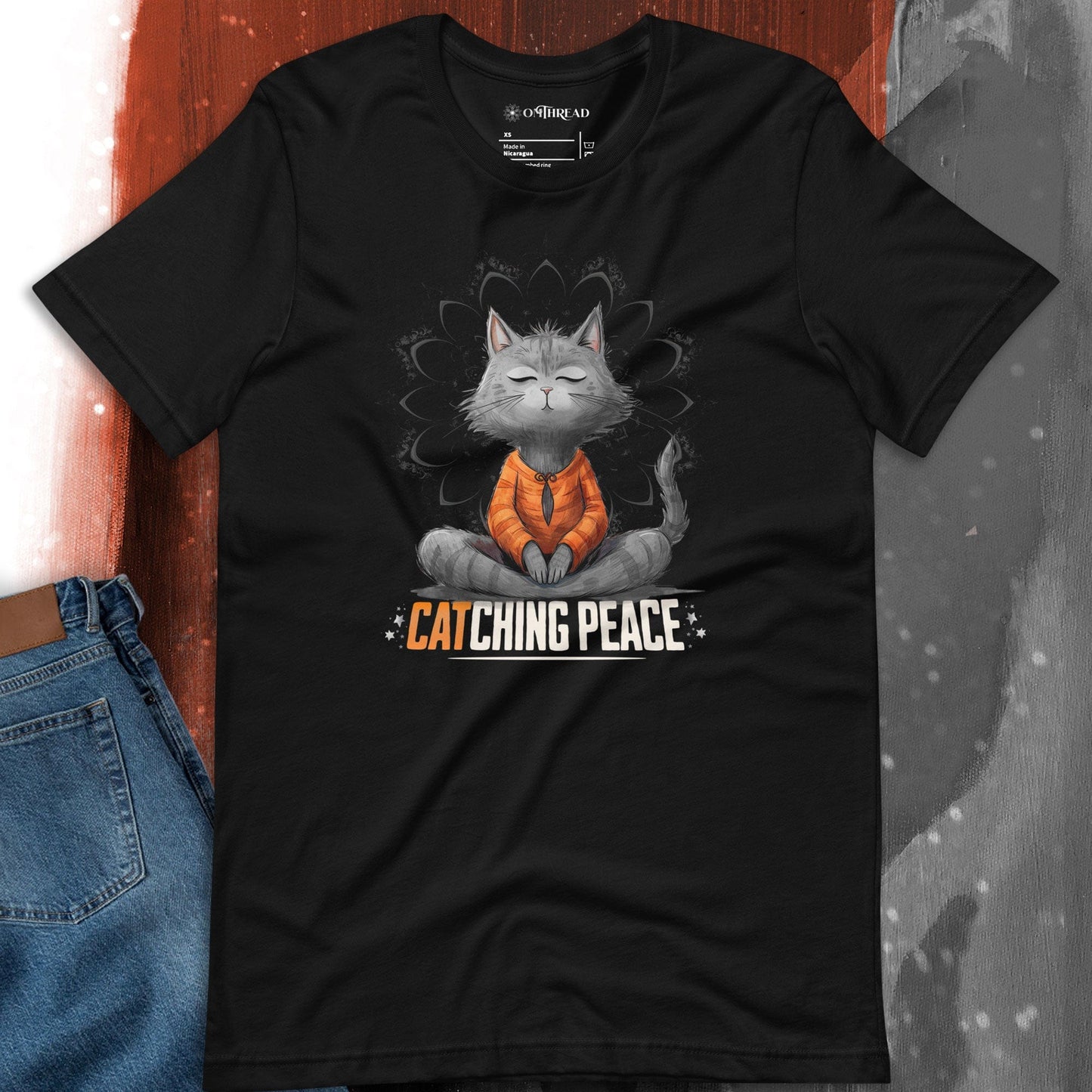 Black t-shirt featuring a meditating cat in a peaceful lotus pose, surrounded by a mandala-inspired design. Below the cat, the text reads 'Catching Peace' in bold typography. Ideal for yoga lovers, mindfulness seekers, and cat enthusiasts.