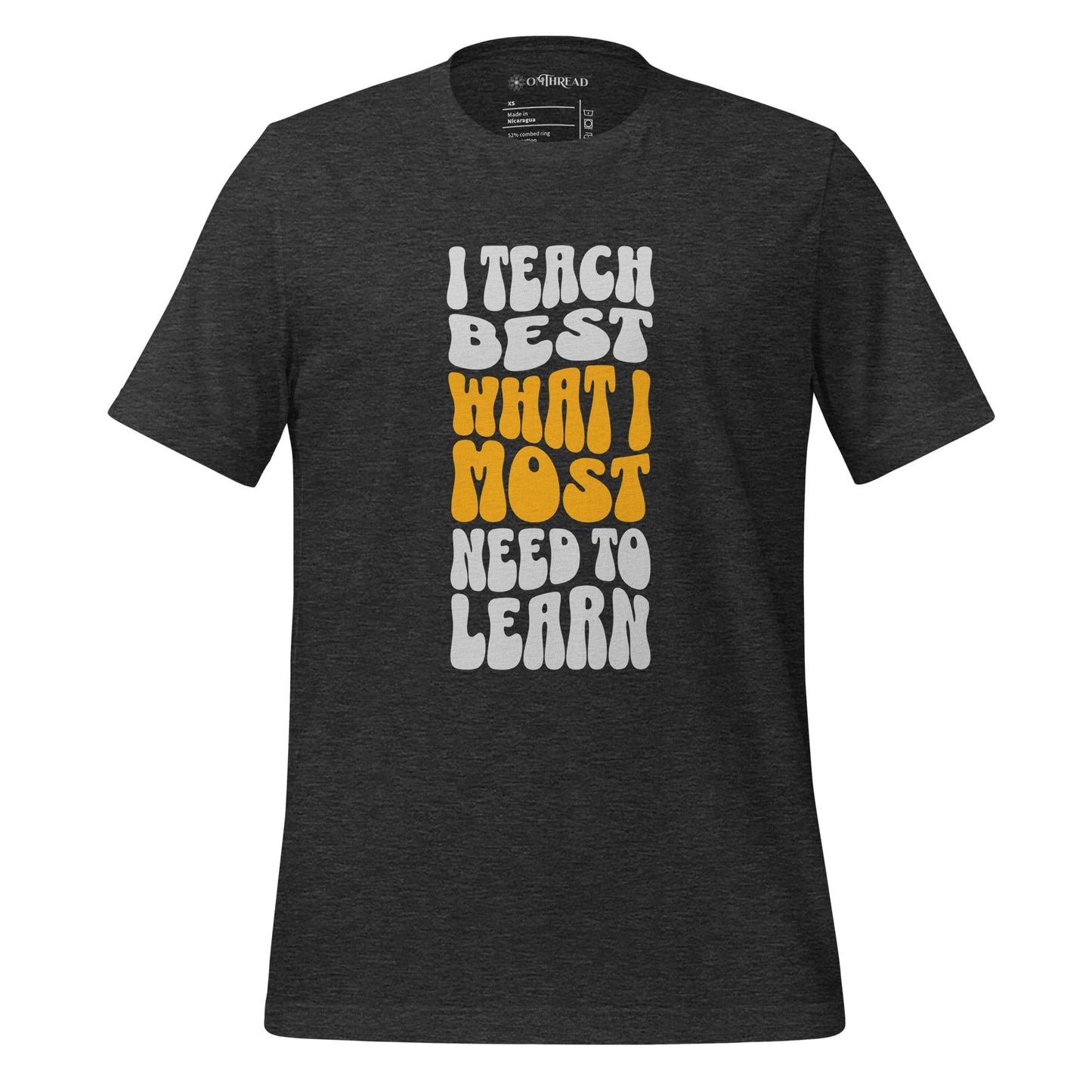 OMTHREAD dark grey heather t-shirt with bold white and yellow text reading "I Teach Best What I Most Need to Learn" in a retro-style font.
