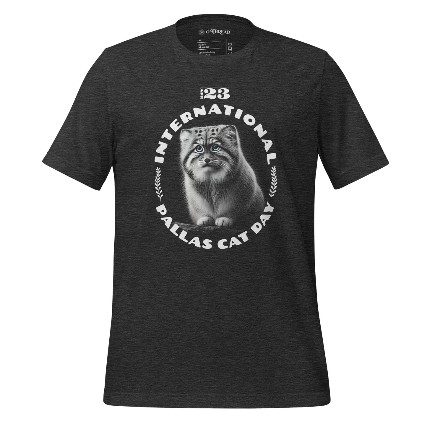 OMThread dark gray t-shirt featuring a detailed black-and-white illustration of a Pallas cat inside a circular design. The words "International Pallas Cat Day" arch around the cat, with "April 23" positioned above.