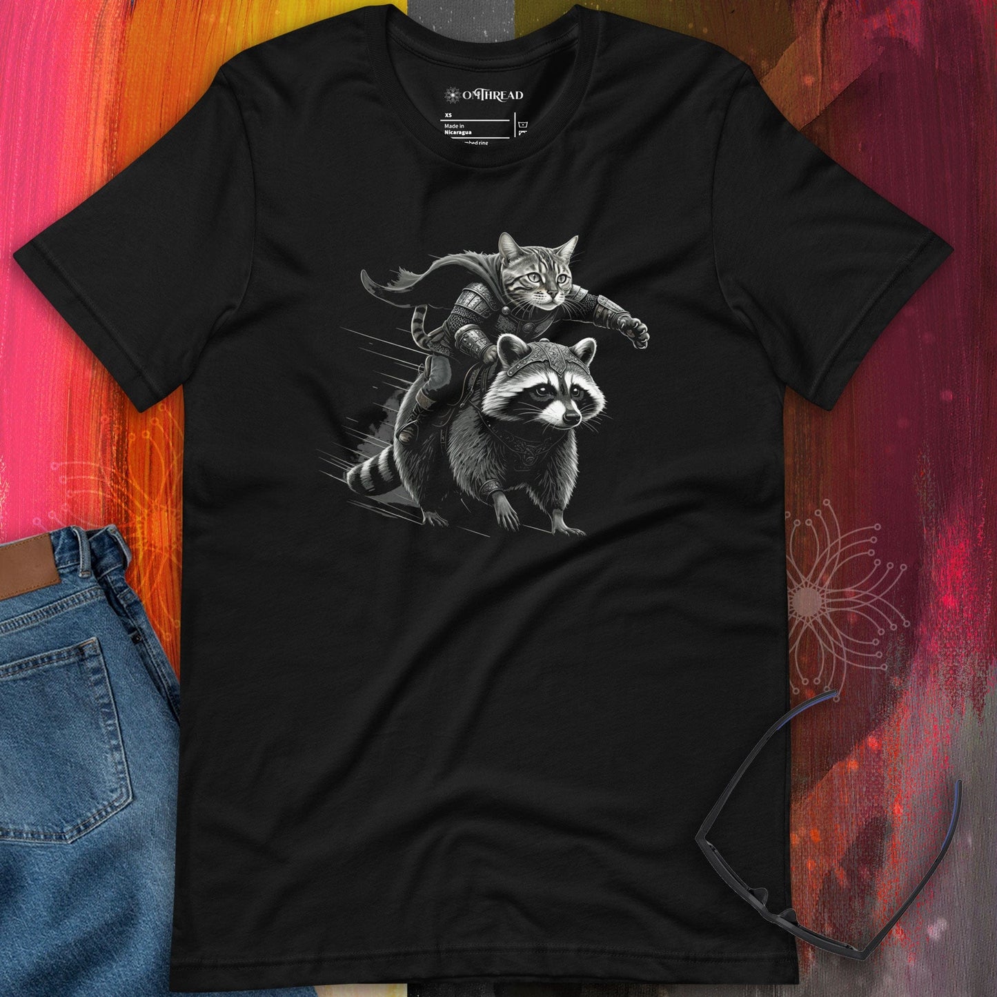 OMThread Viking Cat Warrior black t-shirt featuring an illustration of a fierce cat dressed in Viking armor, gripping a sword while riding a determined raccoon.