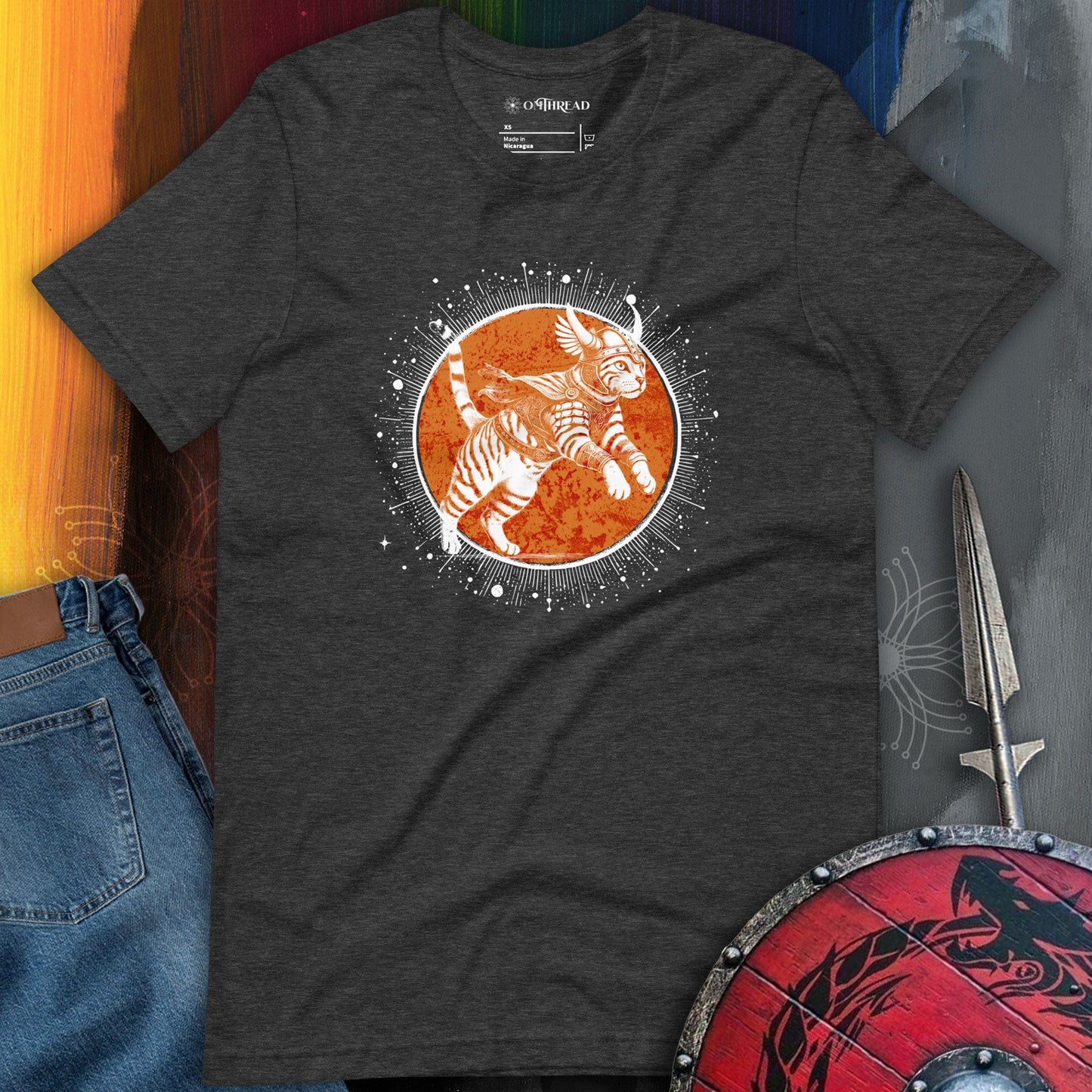 OMThread Epic Warrior Cat dark gray T-Shirt featuring an illustration of a feline dressed in Norse-inspired armor, leaping against a celestial orange backdrop with intricate details. The design highlights Viking mythology influences and a cosmic warrior theme.