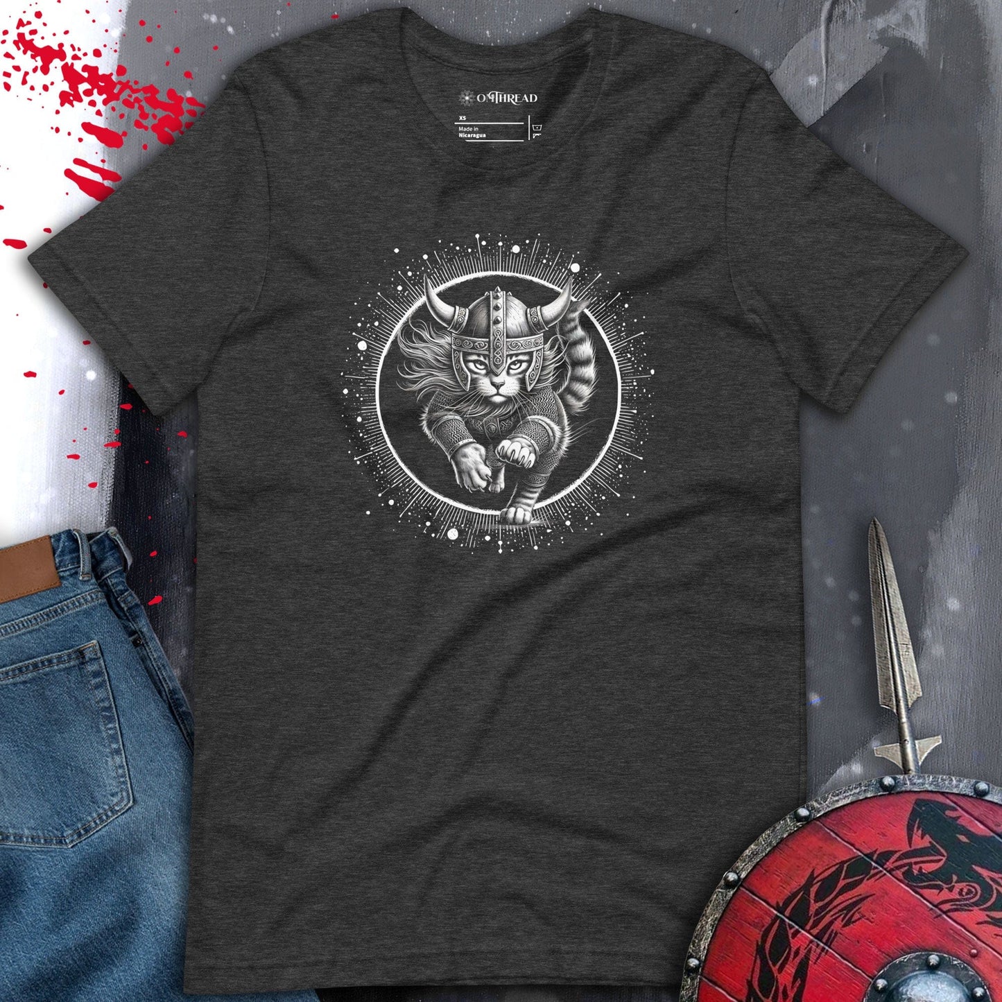 Dark gray t-shirt featuring a Viking cat warrior leaping forward, wearing a horned helmet and armor, set against a cosmic circular background with radiant lines.