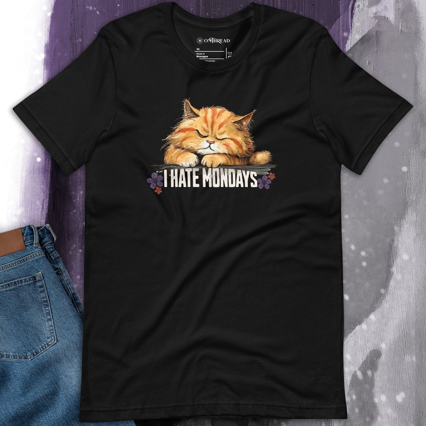 OMTHREAD I Hate Mondays Cat T-Shirt – Funny Lazy Cat Graphic Tee for Pet Lovers on a Black Tee. Features a grumpy orange tabby cat resting on a wooden sign with floral details.