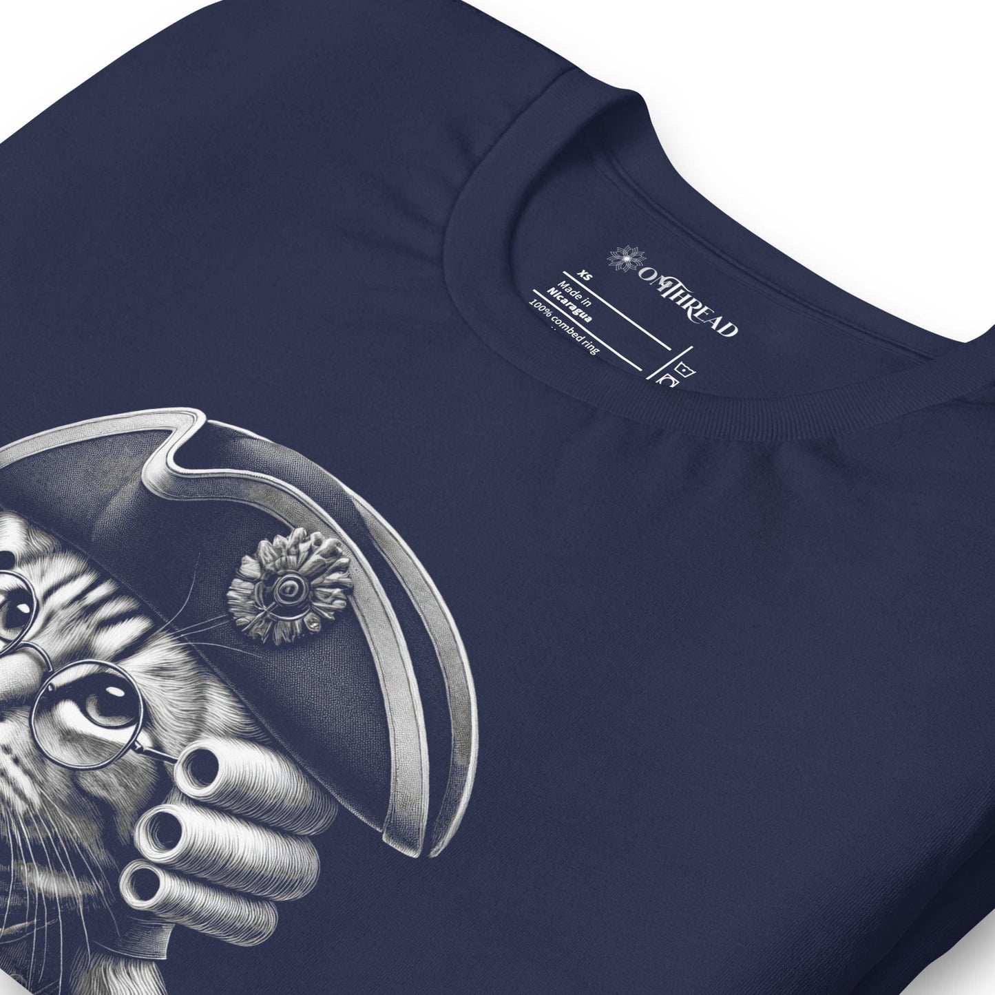 Navy blue t-shirt featuring a distinguished cat dressed in revolutionary attire, complete with a tricorn hat, glasses, and powdered wig. The design includes the phrase, In Whiskers We Trust displayed on a decorative banner beneath the cat.
