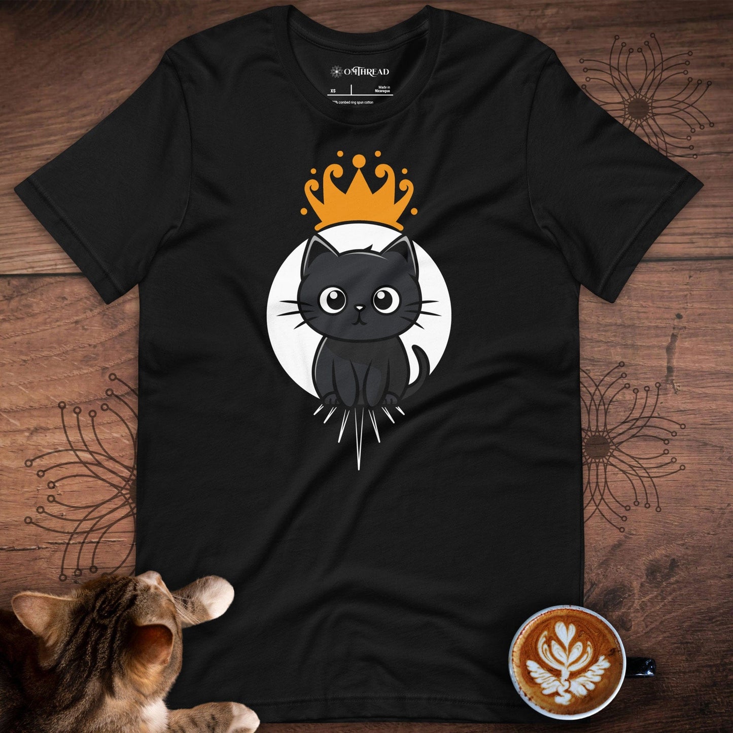 OMThread black t-shirt featuring a cute black cat sitting inside a white circular frame with a golden crown above its head. The design has a minimalist and modern style with clean lines and a playful, regal theme.
