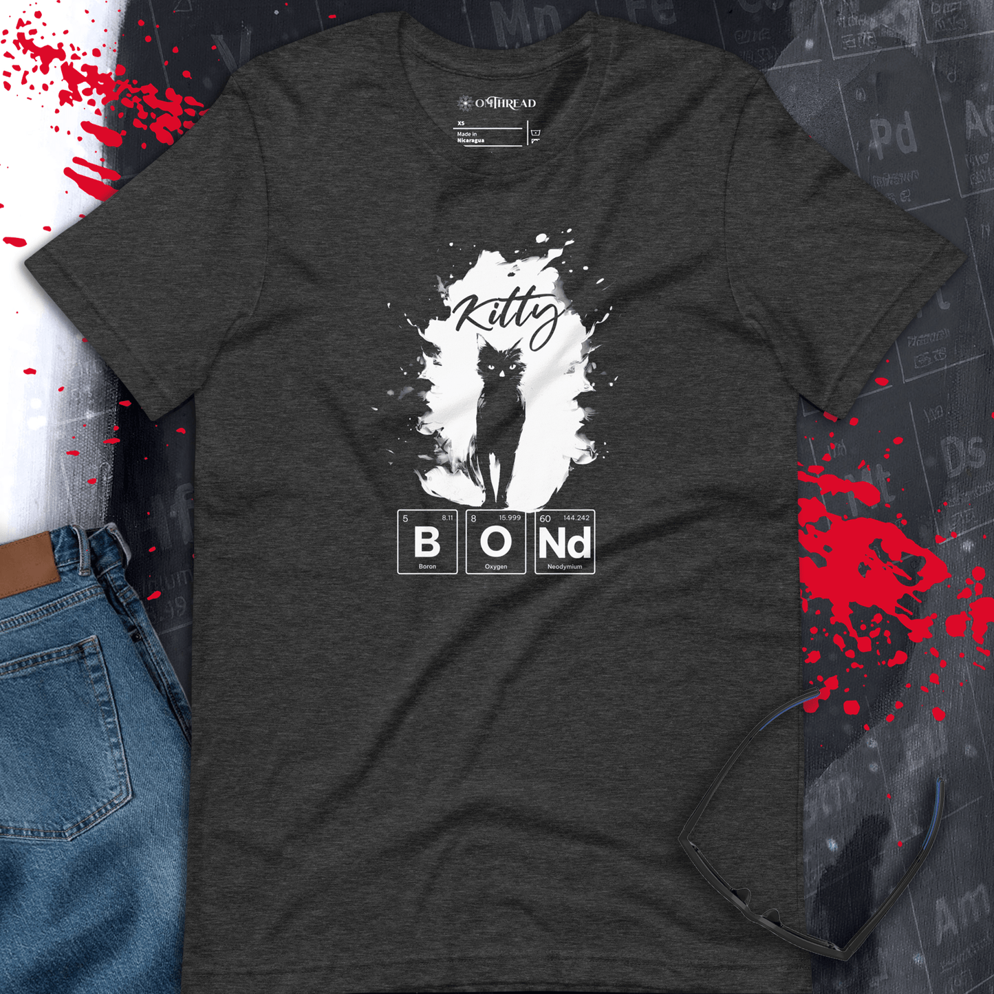 OMTHREAD dark gray t-shirt featuring a black cat silhouette inside a white paint splatter. The word "Kitty" is written in cursive above, and "BOND" is spelled out using periodic table elements.