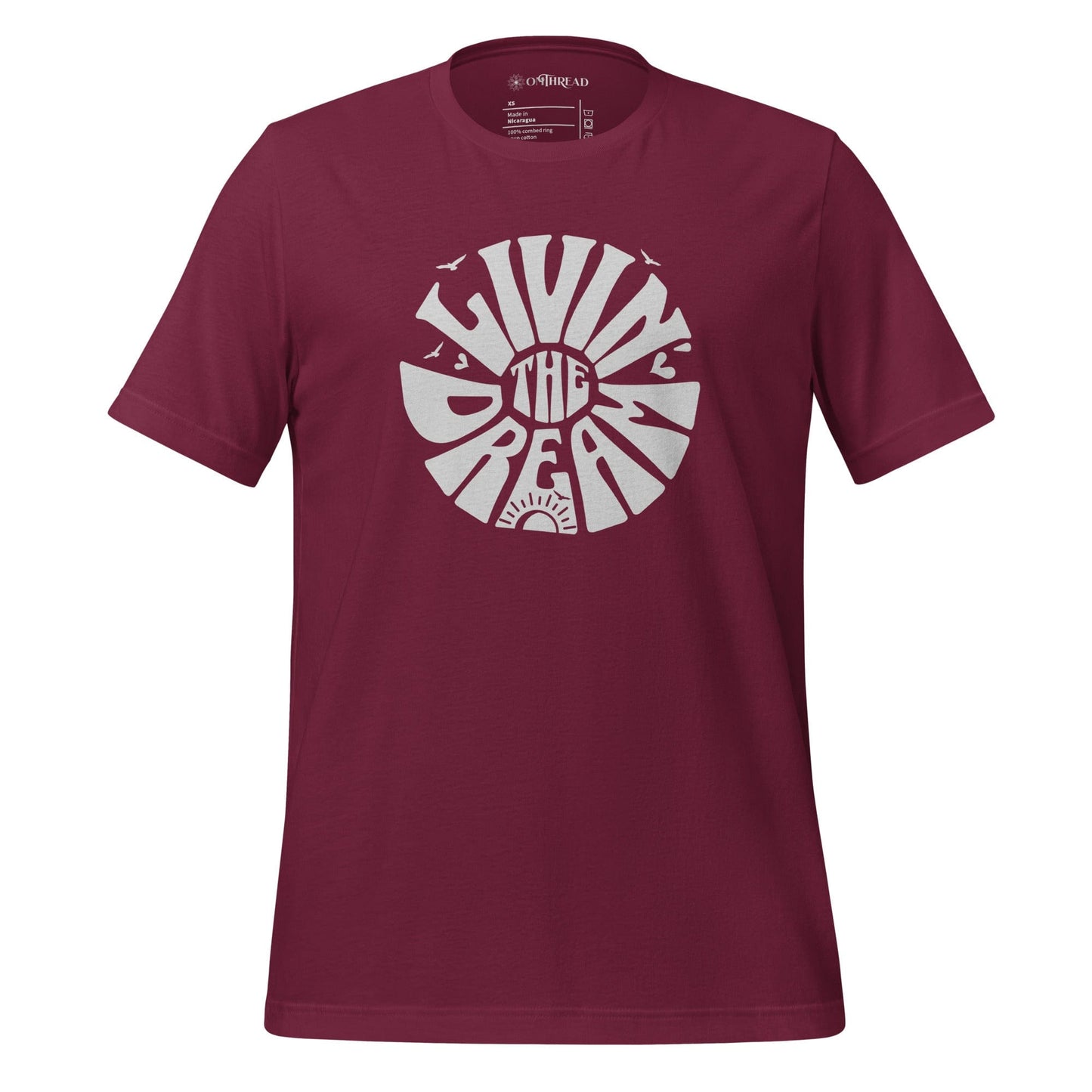 OMTHREAD maroon t-shirt featuring white retro-style typography reading "Livin' the Dream" in a circular design with sun, birds, and heart elements.