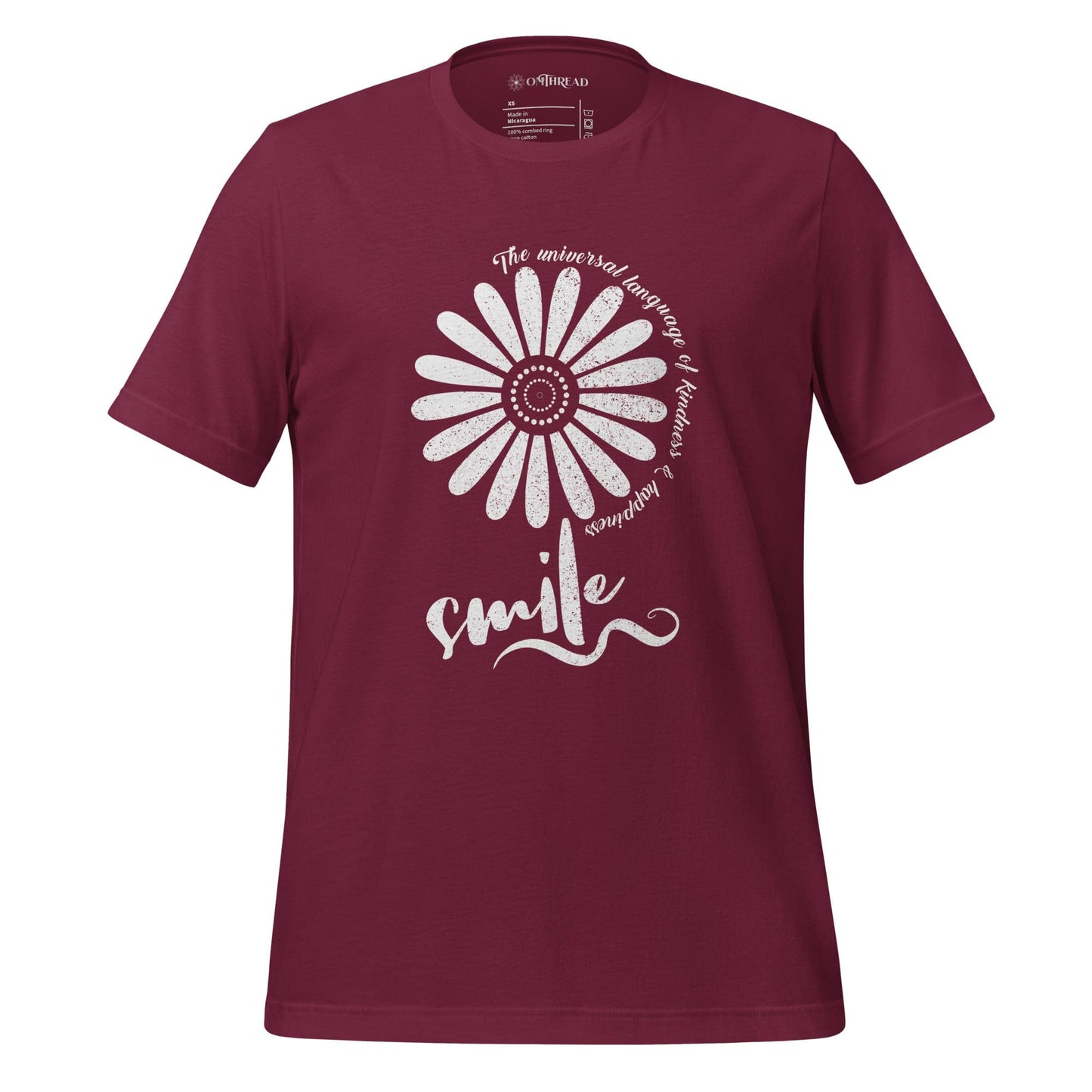 OMTHREAD maroon t-shirt with a white floral design and the word "smile" in script, surrounded by the phrase "The universal language of kindness & happiness" in a circular pattern