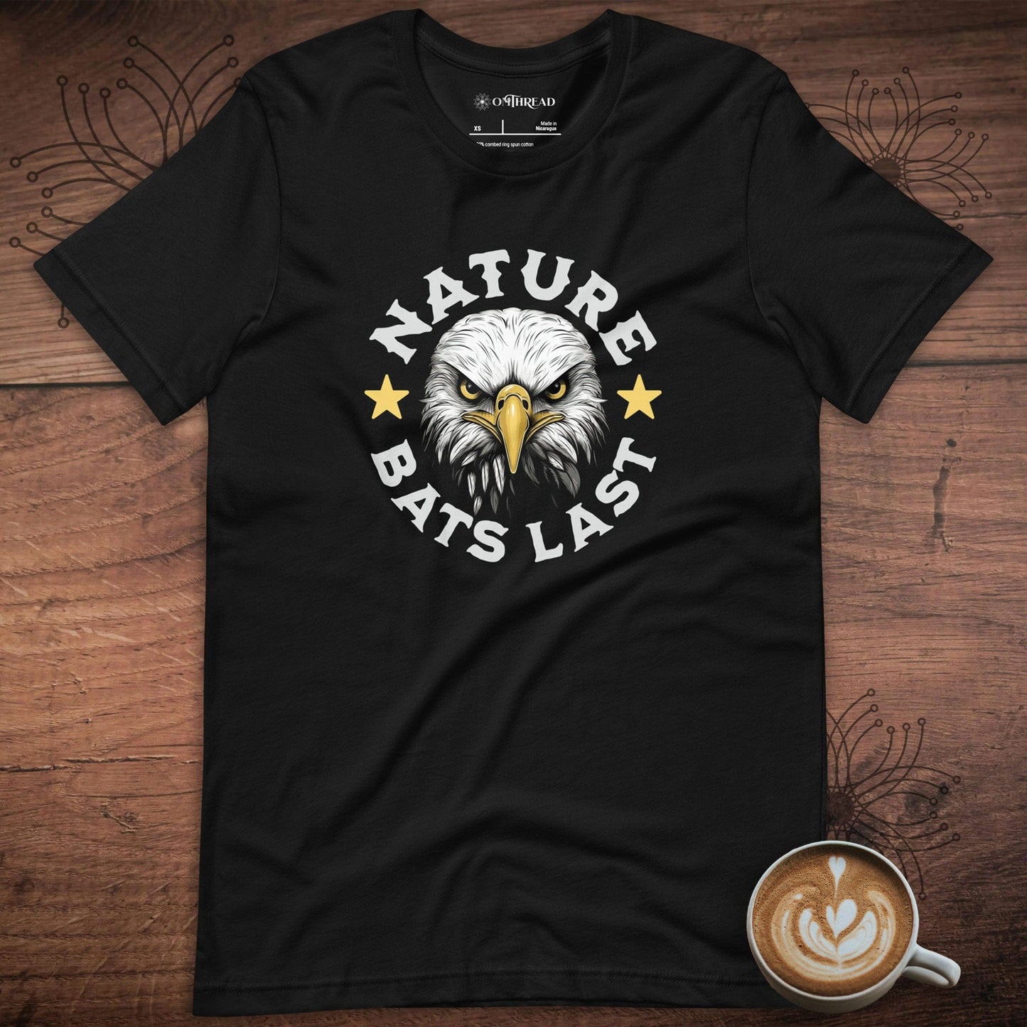 OMTHREAD black t-shirt featuring a fierce bald eagle illustration with "Nature Bats Last" text in bold white letters, accented by two yellow stars.