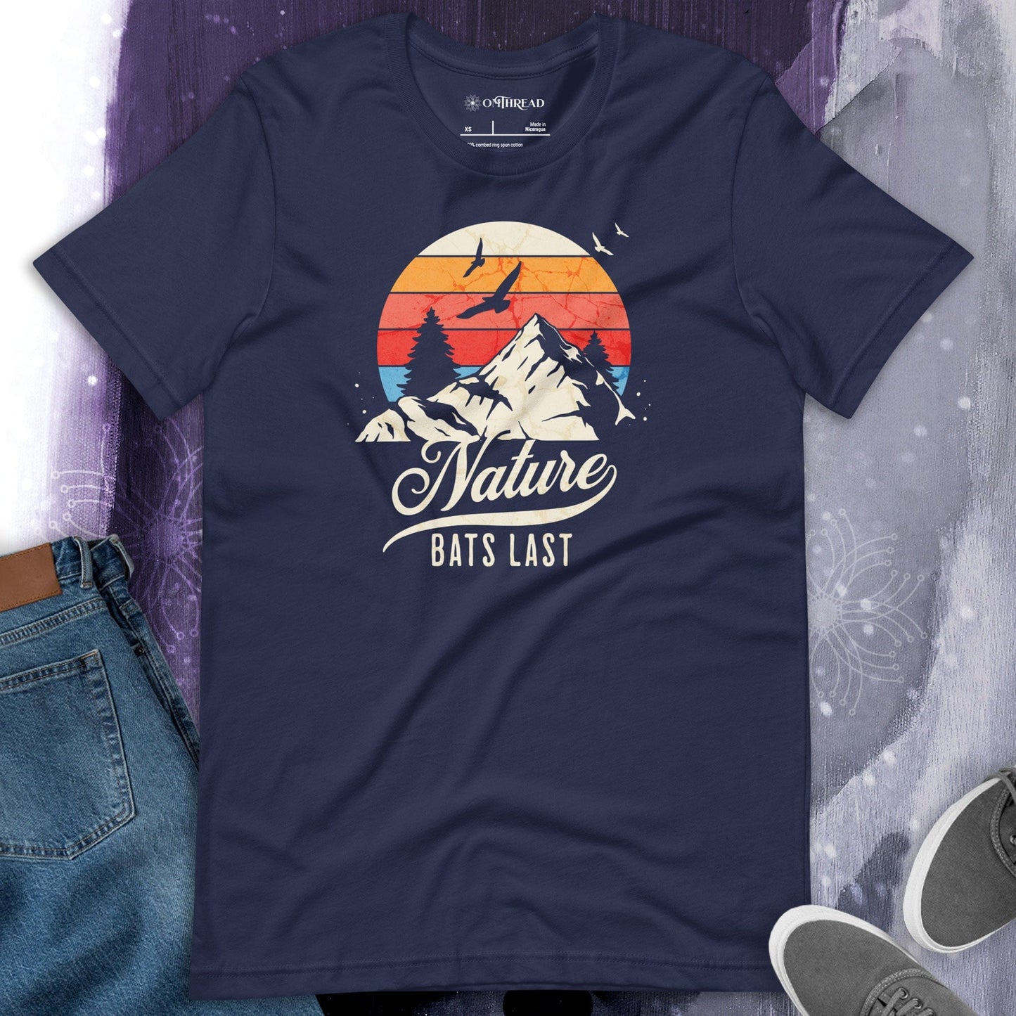 OMThread navy blue t-shirt featuring a retro-style mountain landscape with a sunset and birds in flight, displaying the phrase "Nature Bats Last" in vintage typography.