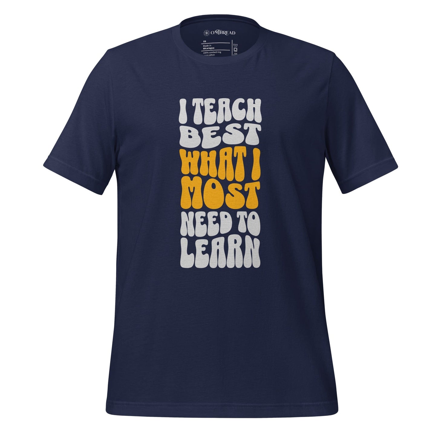 OMTHREAD navy t-shirt with bold white and yellow text reading "I Teach Best What I Most Need to Learn" in a retro-style font.