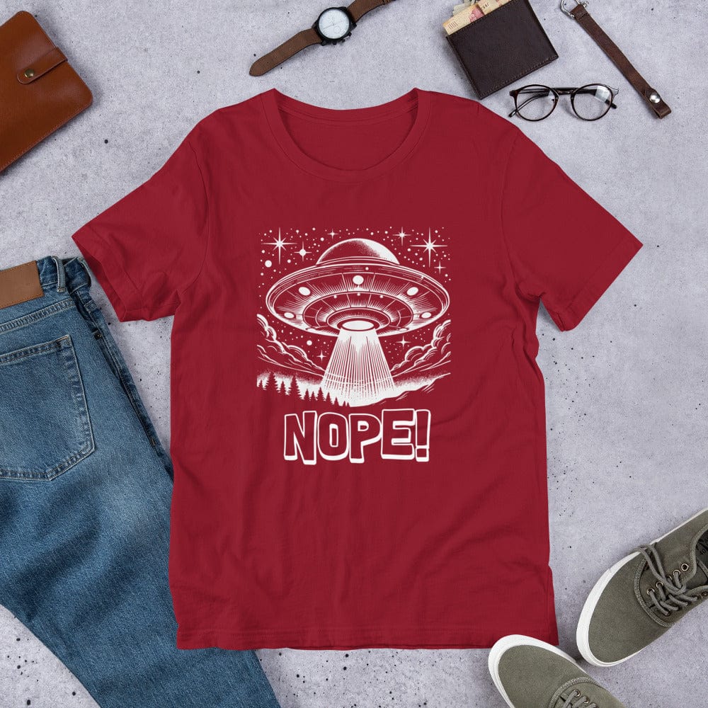 Crimson red t-shirt featuring a retro-style illustration of a UFO beaming light down onto a forest, surrounded by stars and clouds, with the bold text, NOPE! emphasizing humor and alien themes