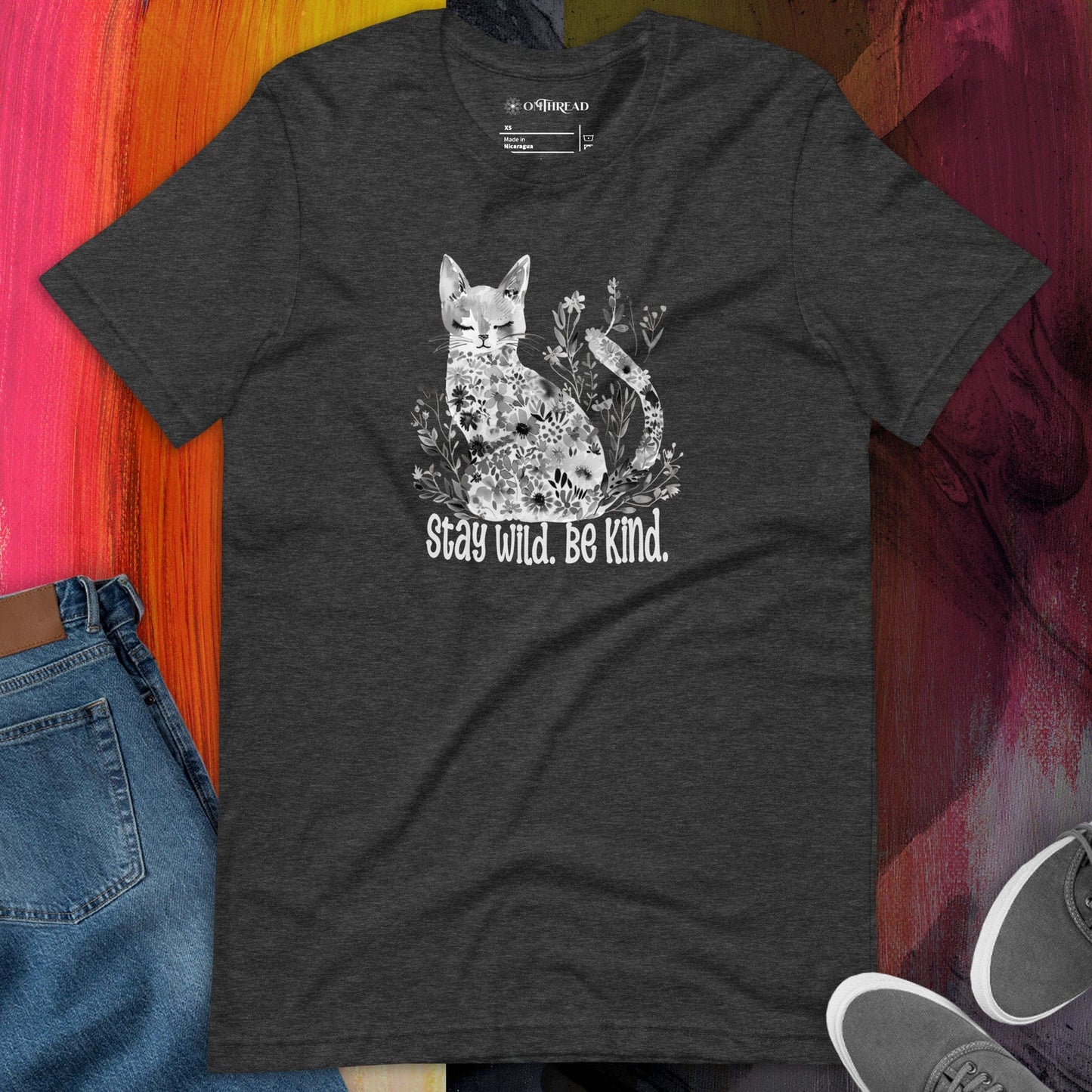 OMThread Stay Wild Be Kind dark gray t-shirt featuring a white floral cat illustration with "Stay Wild. Be Kind." text in a handwritten-style font.