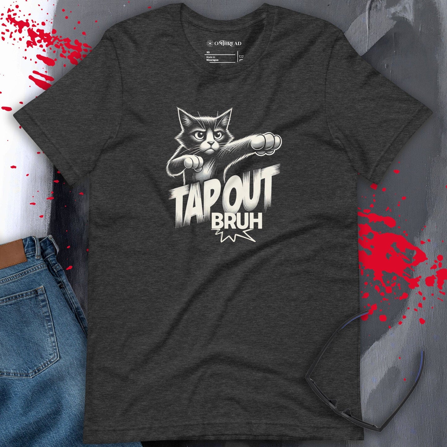Dark gray t-shirt featuring a comic-style design of a fierce black-and-white cat throwing punches. The text 'TAP OUT BRUH' appears in bold, dynamic lettering.