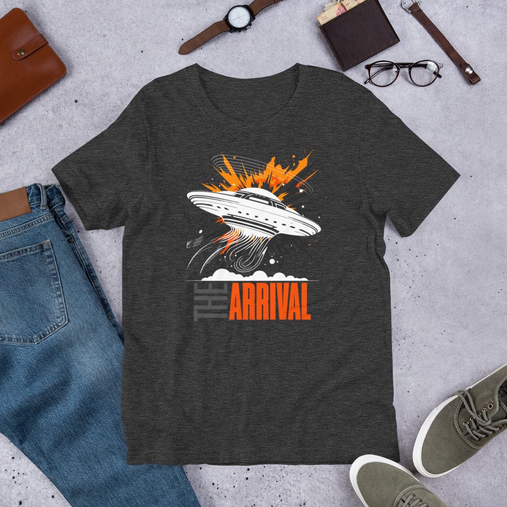 Dark gray t-shirt showcasing a bold design of a UFO emitting glowing beams, surrounded by explosive orange accents, clouds, and dynamic motion lines, with the text, THE ARRIVAL in contrasting gray and orange, blending sci-fi and graphic art.