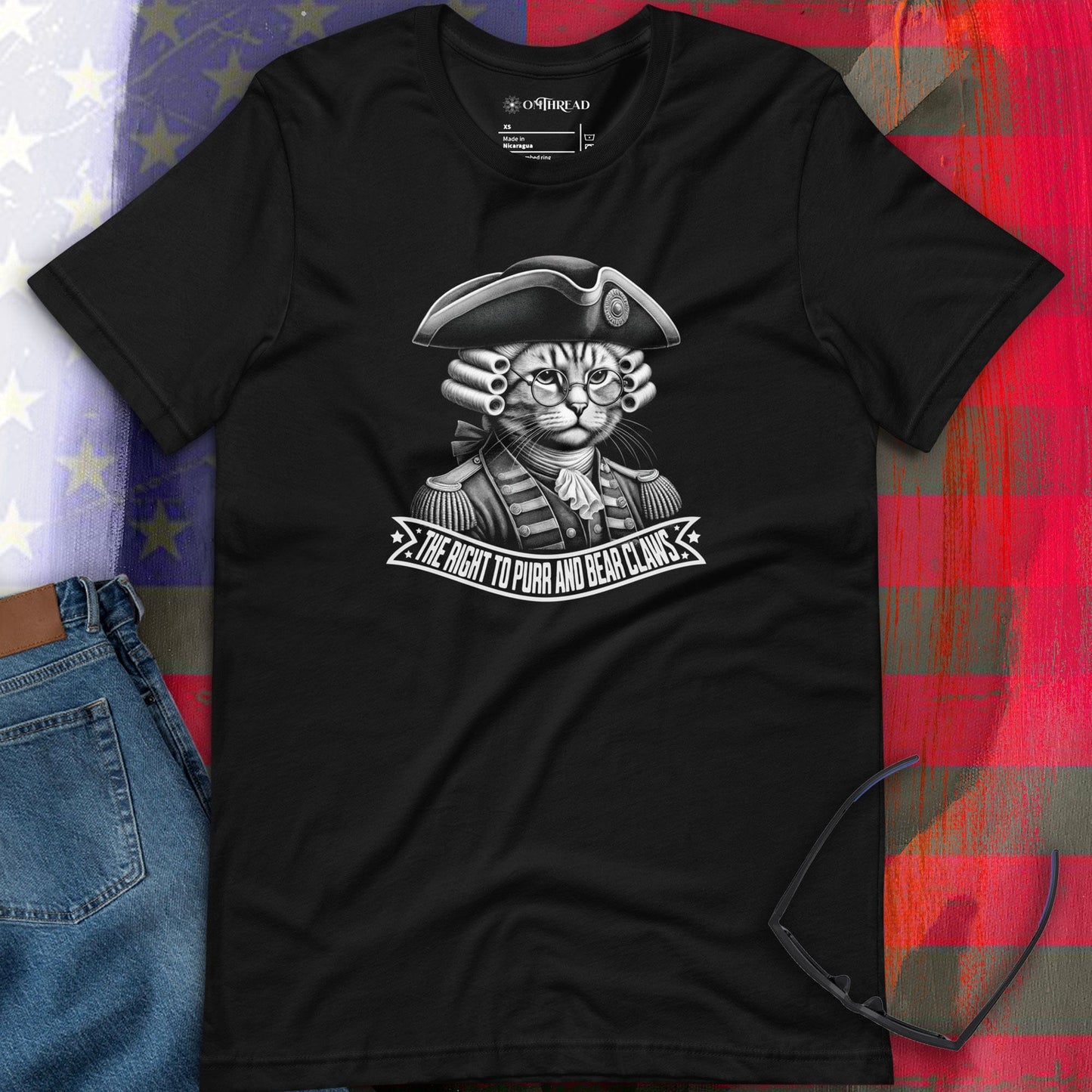 MThread black t-shirt featuring a cat in 18th-century revolutionary attire, complete with a tricorn hat, powdered wig, and glasses. The design includes a bold banner reading 'The Right to Purr and Bear Claws' in stylized lettering.