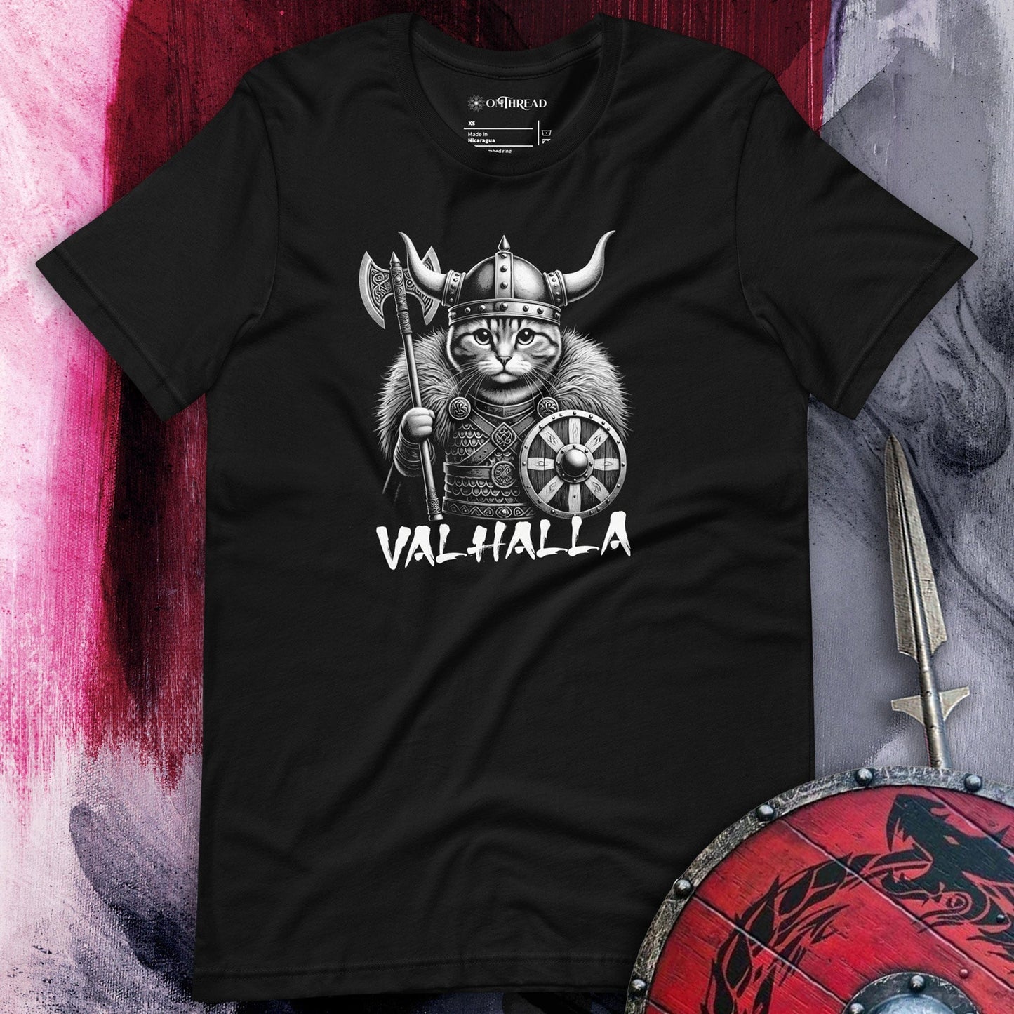 Black t-shirt featuring a Viking cat warrior wearing a horned helmet, fur cloak, and armor, holding an axe and shield. The word 'VALHALLA' is displayed below.