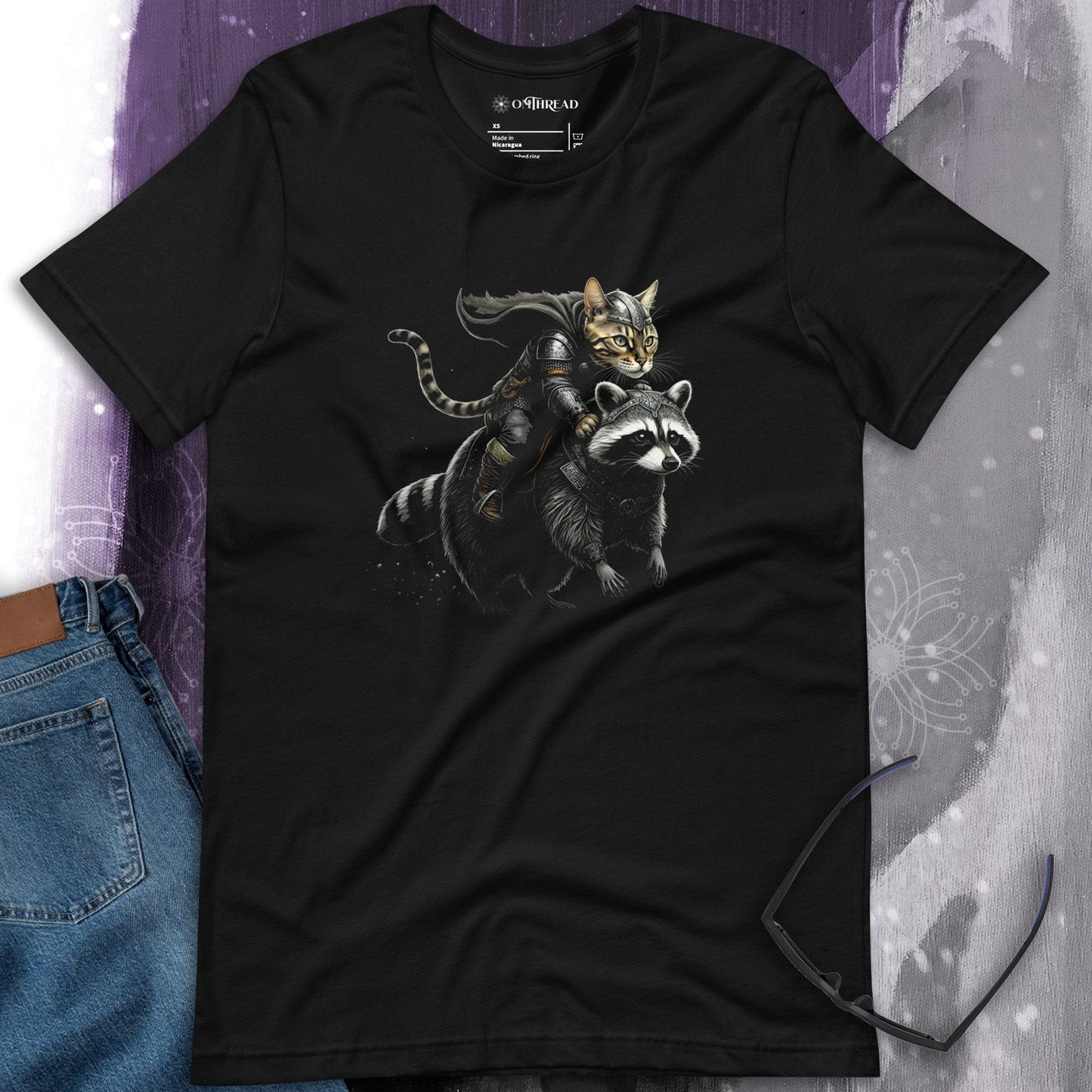 OMThread Viking Bengal Cat Raccoon Rider black t-shirt featuring a detailed illustration of a Bengal cat dressed as a Viking warrior, wearing armor and holding a sword, while riding a strong, armored raccoon.