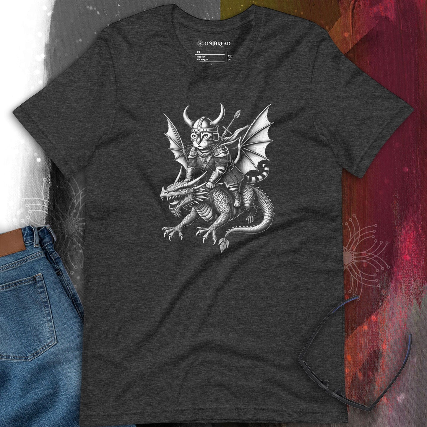 OMThread Viking Cat Dragon Rider dark gray t-shirt featuring a detailed black and white illustration of a feline warrior in Viking armor, holding a spear while riding a fierce dragon with large wings and sharp claws.