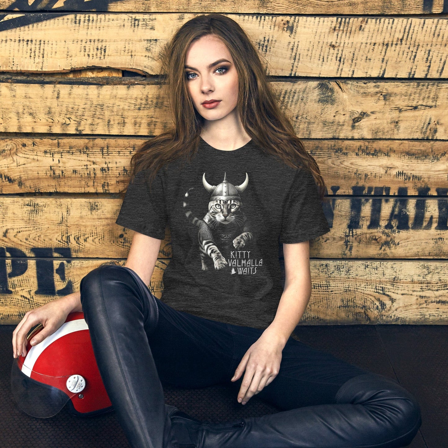 A female model wearing a dark gray t-shirt featuring a Viking-themed design of a fierce bengal cat wearing a horned helmet and armor. The text below reads 'Kitty Valhalla Waits' in bold, stylized font.