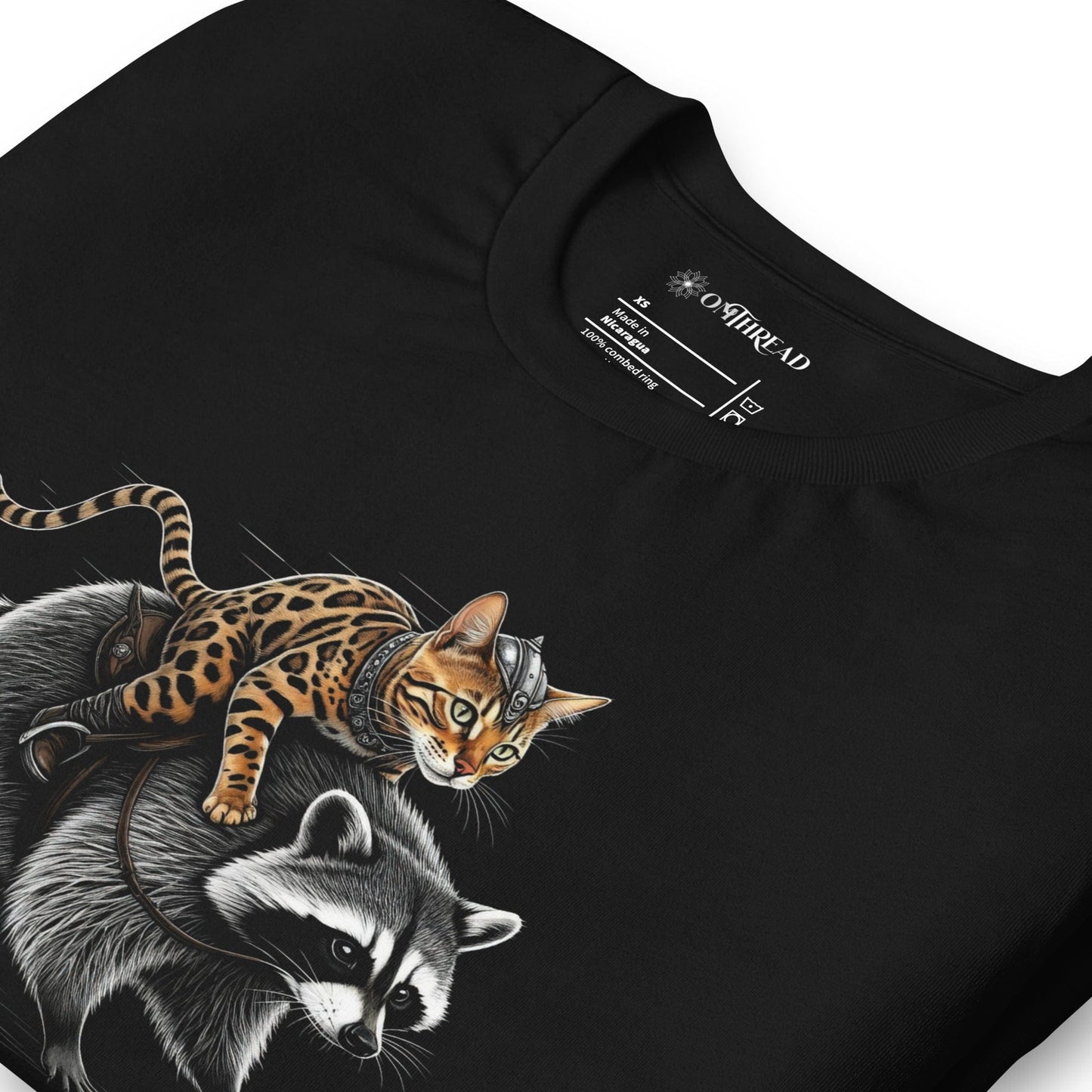 OMTHREAD black t-shirt featuring a Viking warrior cat with Nordic markings riding a determined raccoon. The feline has a fierce expression, gripping the raccoon's fur, while the raccoon strides forward with focus.