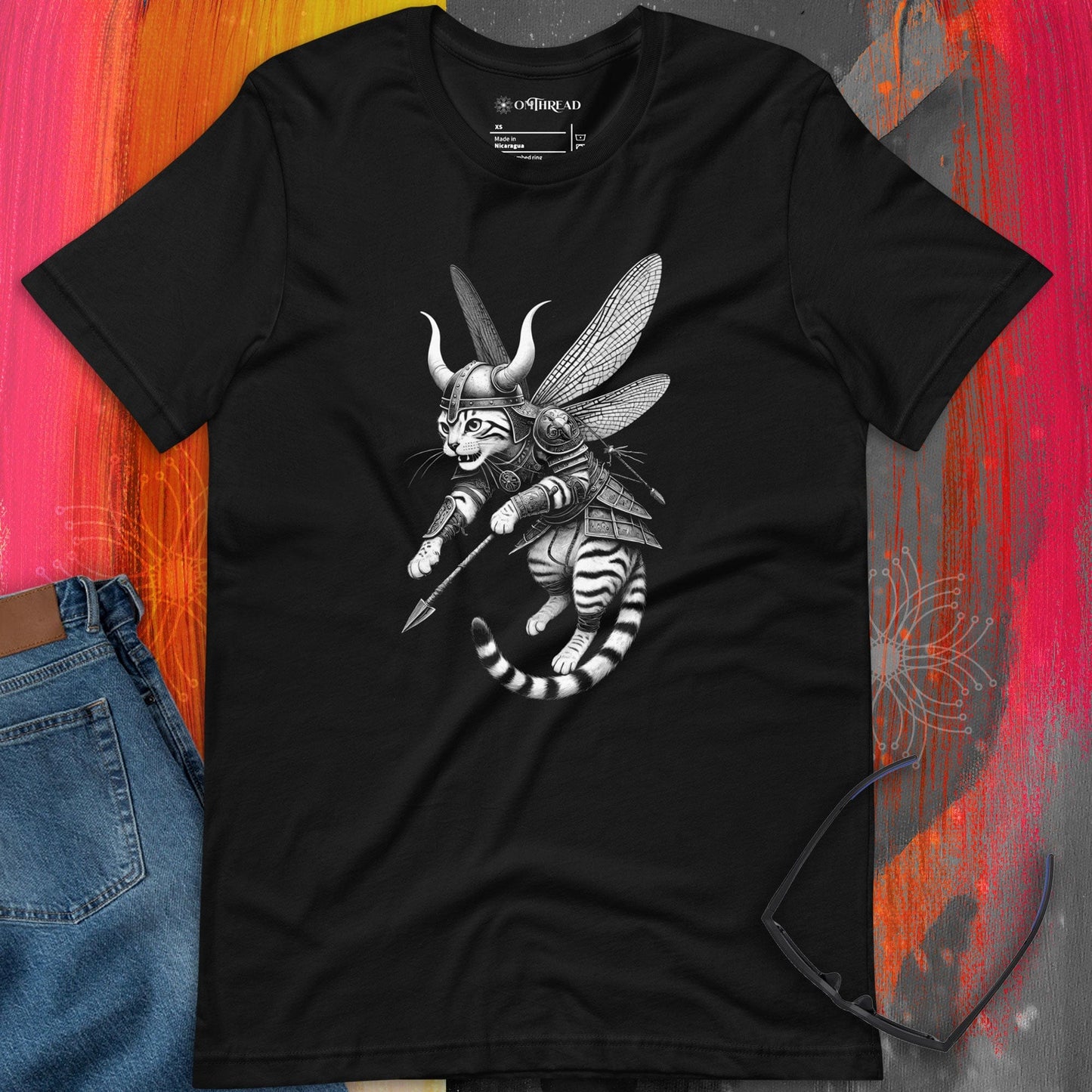OMThread black t-shirt featuring a Viking warrior cat in full armor with dragonfly wings, wielding a spear. The feline has a fierce expression, wearing a horned helmet and detailed armor, blending fantasy and Norse mythology elements.