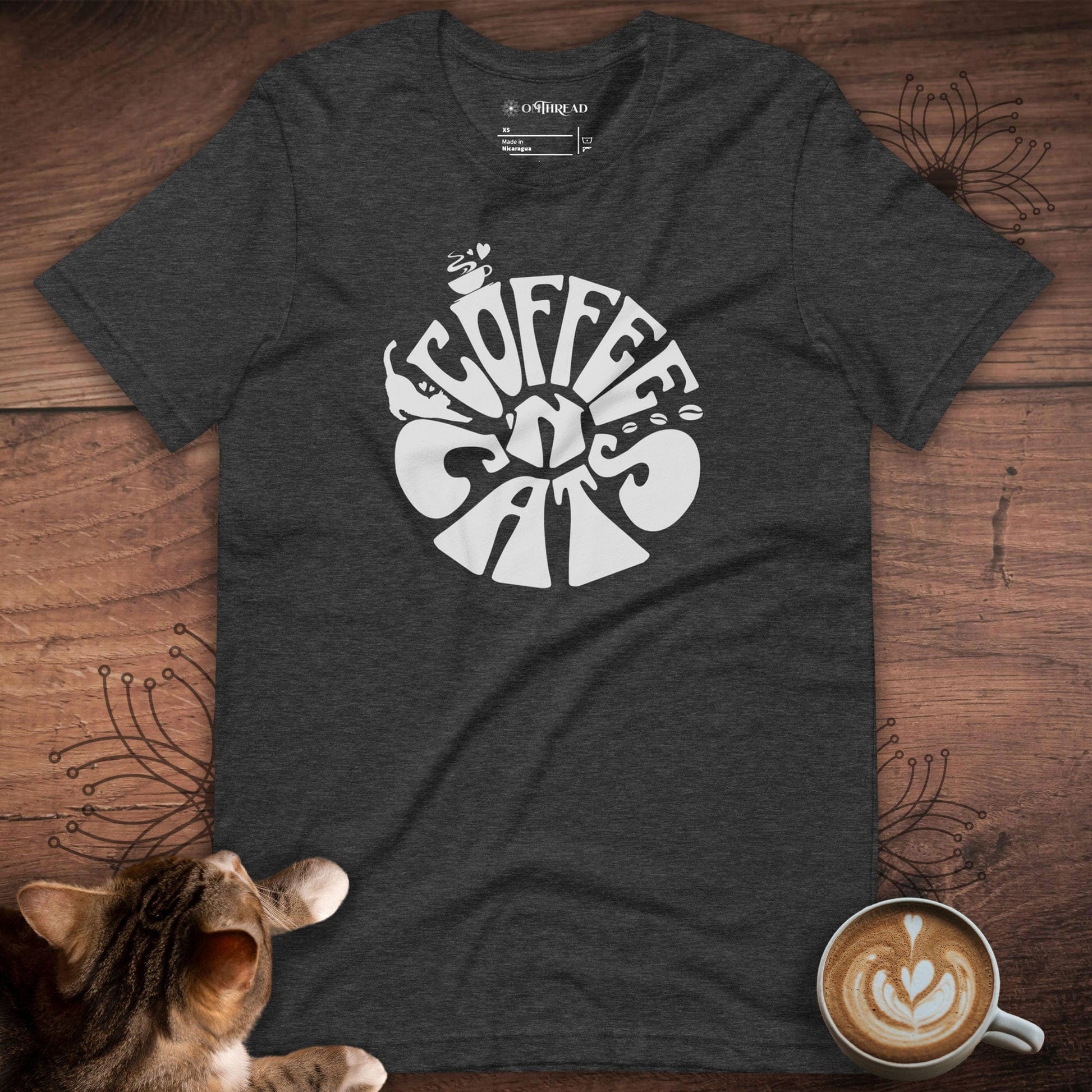 Charcoal t-shirt featuring a retro-style design with the words 'Coffee & Cats' in bold, curvy white lettering. The design includes small illustrations of a steaming coffee cup and a cat silhouette within the text.