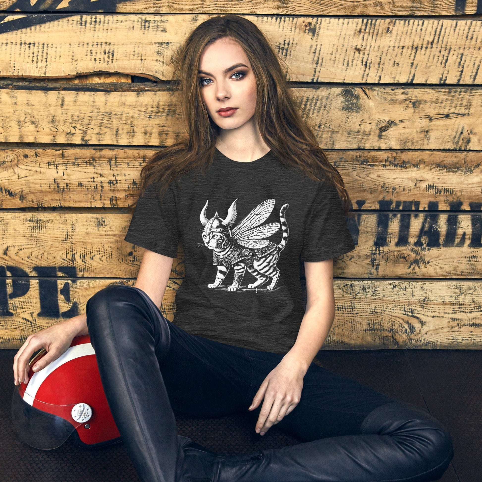 A female wearing a dark gray t-shirt featuring a detailed illustration of a cat dressed as a Viking warrior, complete with armor, horned helmet, and insect-like wings. The cat stands confidently with intricate linework and patterns enhancing the design.