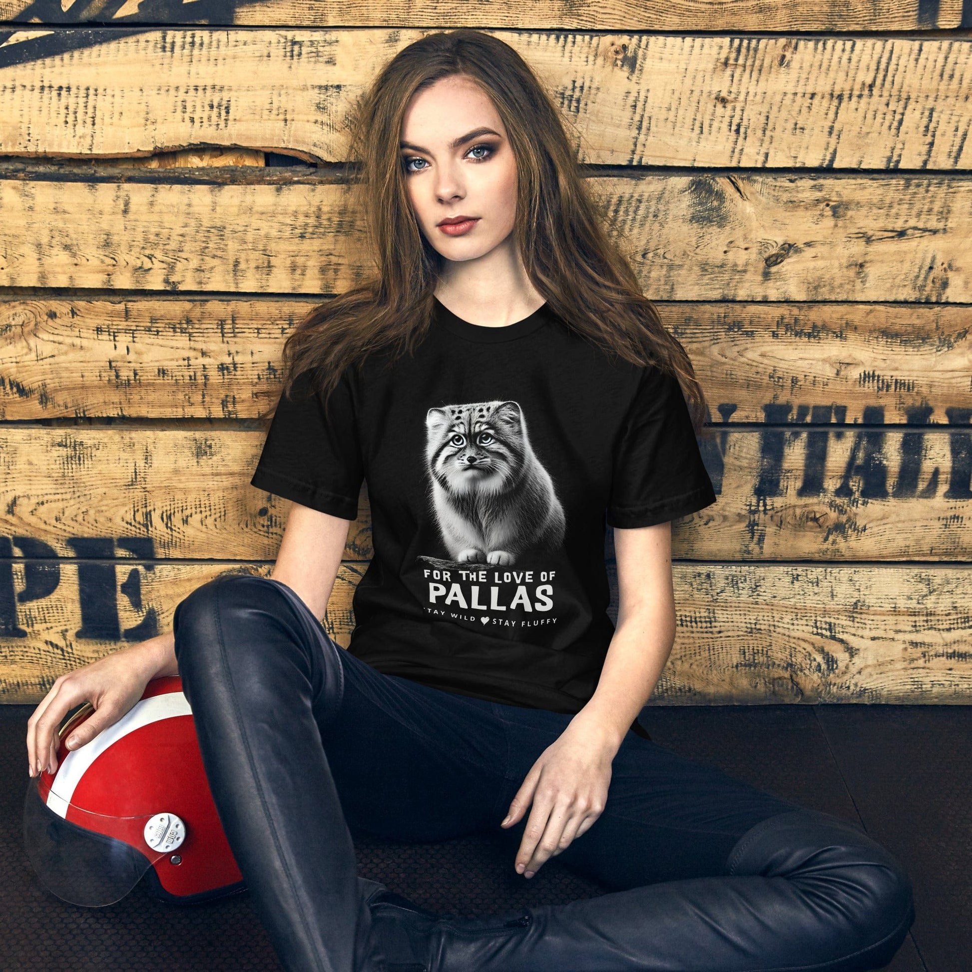 Woman wearing the 'For the Love of Pallas' t-shirt by OMThread in black, set against a rustic wooden background with a relaxed and adventurous vibe. Cat graphic tee | Cute cat t-shirt design | Feline lovers gift | Conservation-themed apparel