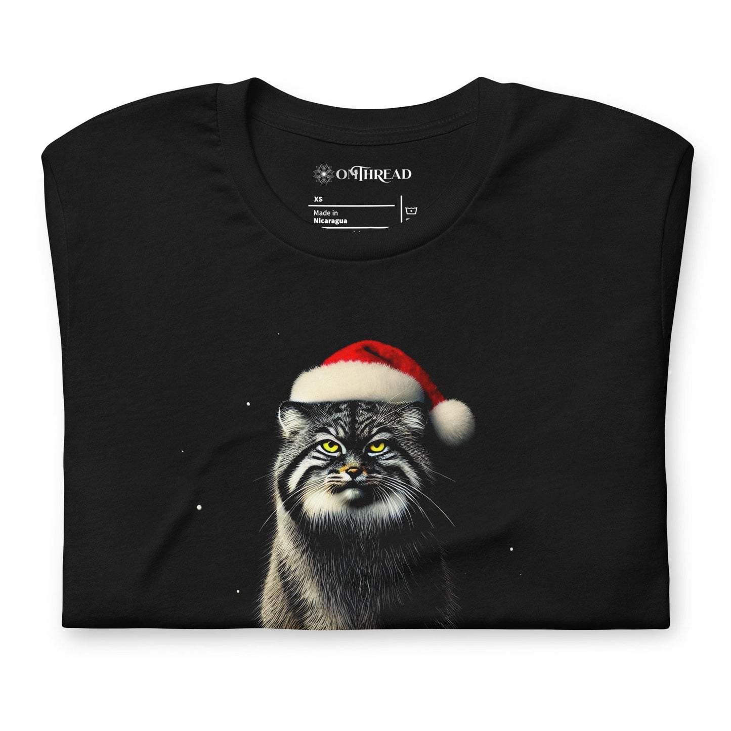 Black t-shirt featuring a Pallas cat wearing a Santa hat, sitting on a snowy rock with a grumpy expression. The text below reads 'GRINCHY PALLAS' in green and red, with the phrase 'My heart grew triple its size' underneath.