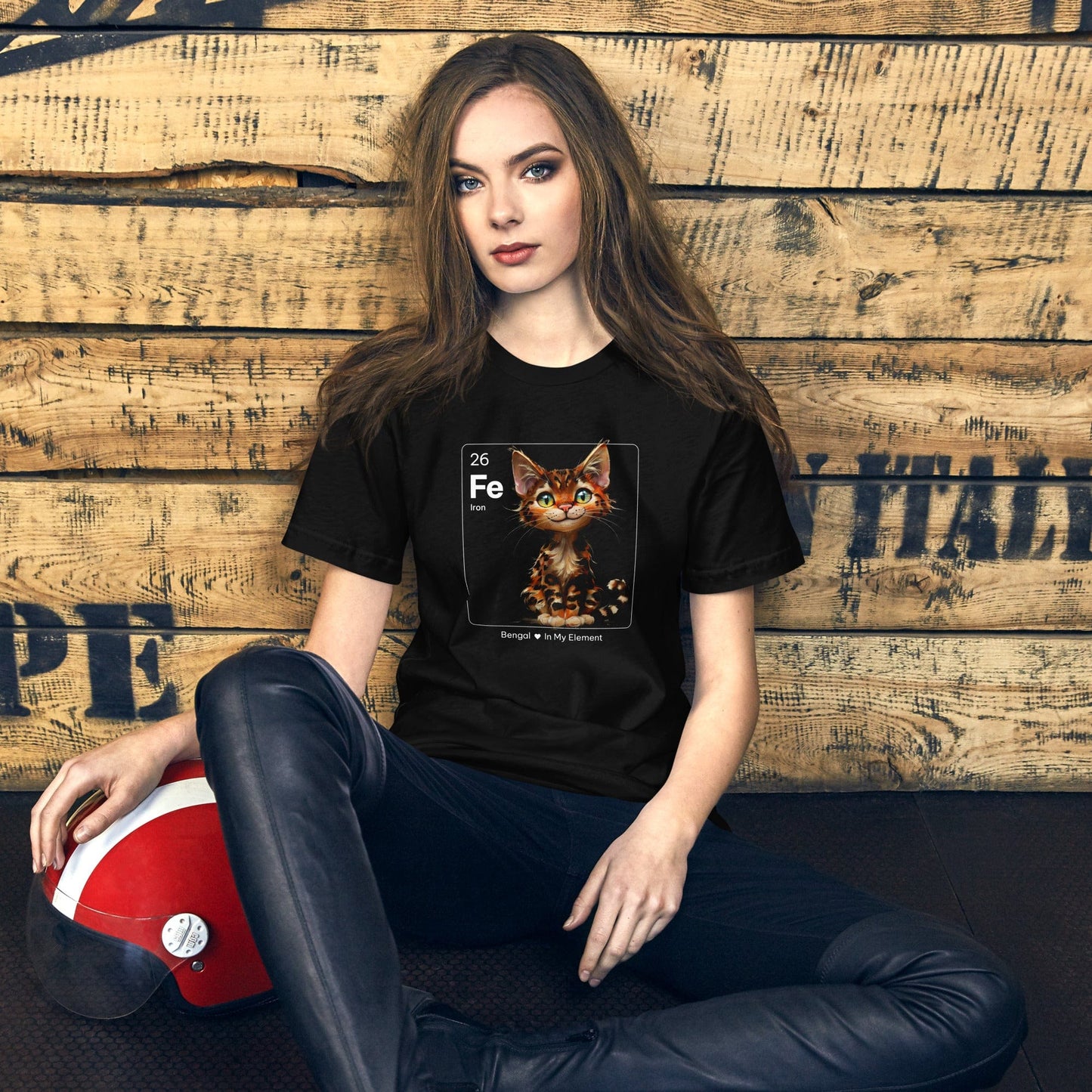 Woman wearing black t-shirt with a periodic table-inspired design featuring a cute, illustrated Bengal cat within a square labeled 'Fe' for Iron. Text below reads 'Bengal In My Element'