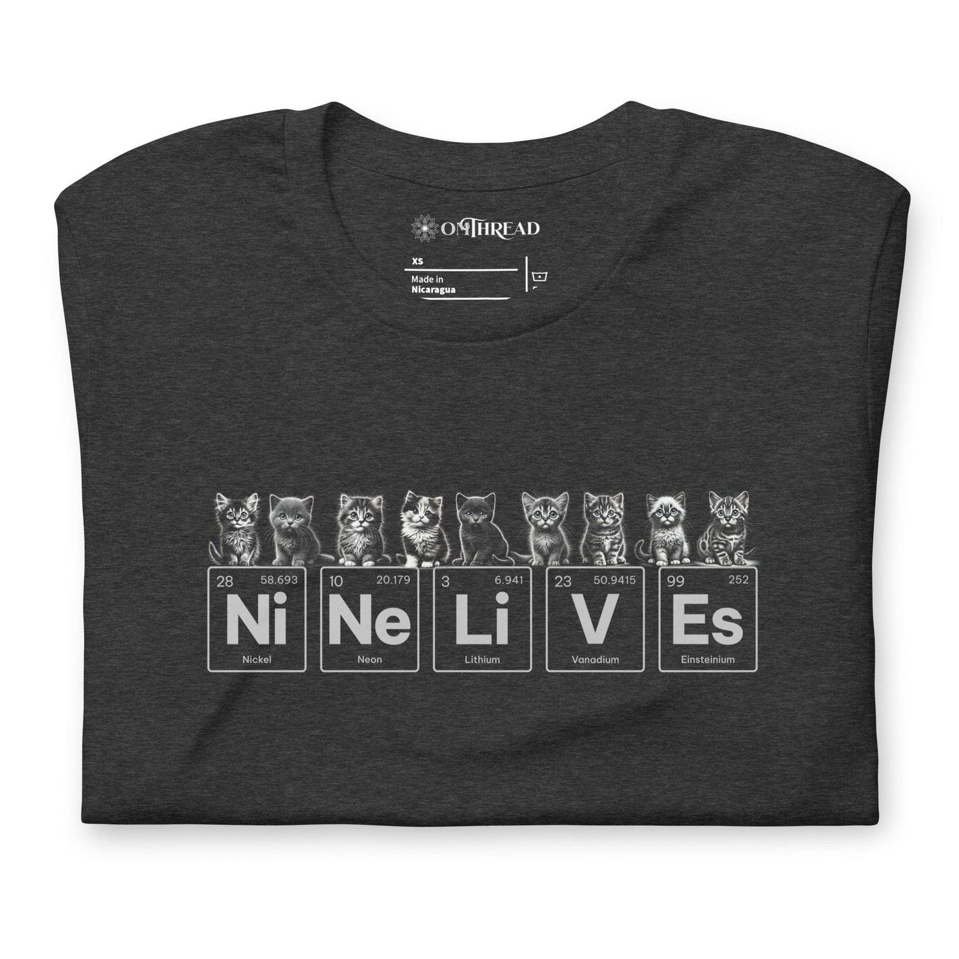 Dark gray t-shirt featuring nine illustrated kittens, each with playful expressions, sitting above periodic table elements that spell 'Ni Ne Li V Es' (Nickel, Neon, Lithium, Vanadium, and Einsteinium), representing 'Nine Lives.