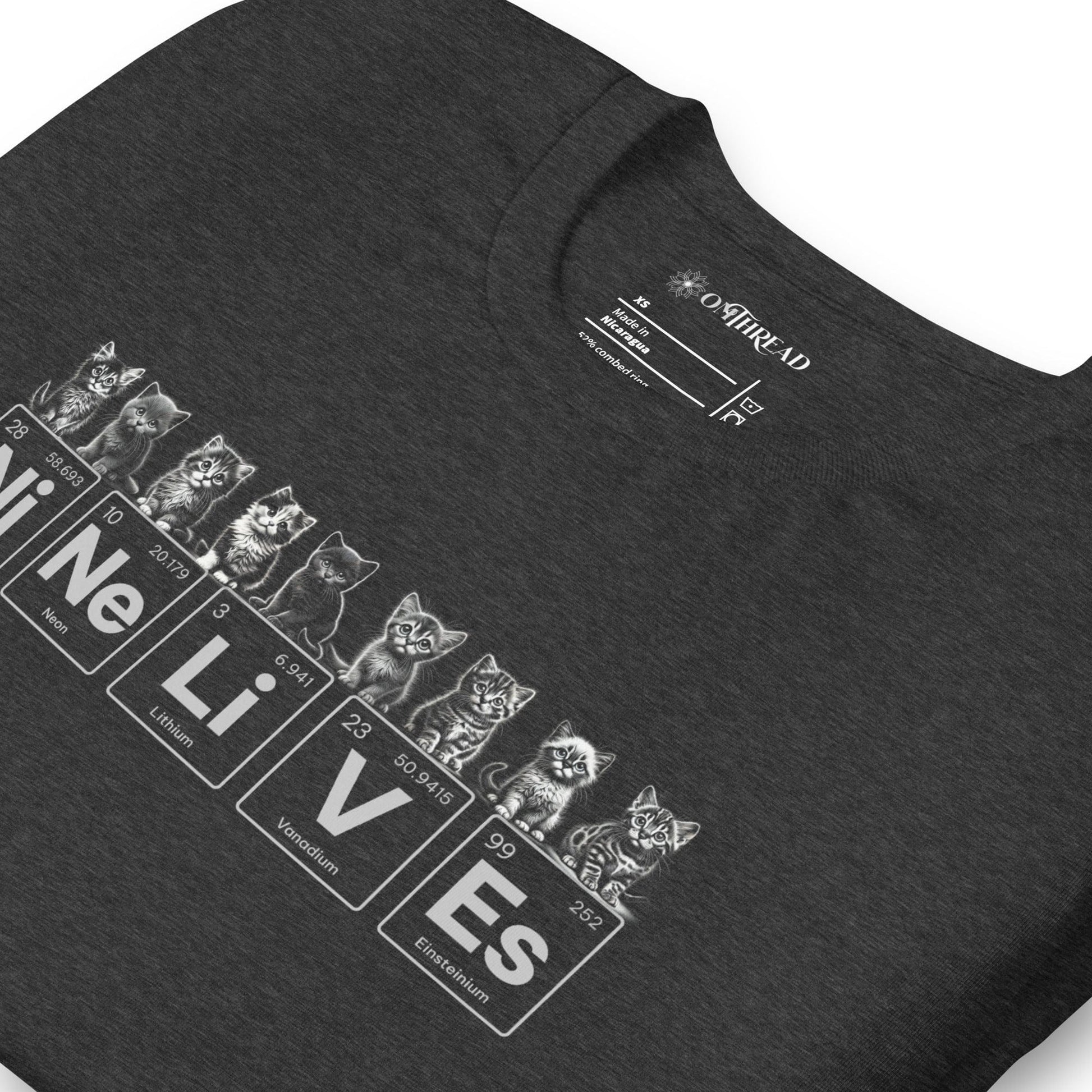 Dark gray t-shirt featuring nine illustrated kittens, each with playful expressions, sitting above periodic table elements that spell 'Ni Ne Li V Es' (Nickel, Neon, Lithium, Vanadium, and Einsteinium), representing 'Nine Lives.