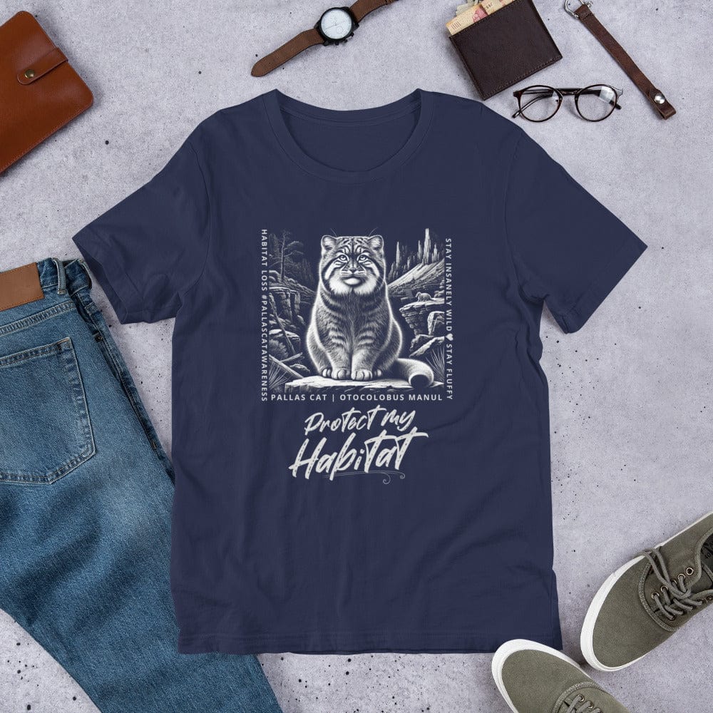 Navy blue t-shirt featuring a detailed black-and-white illustration of a Pallas cat sitting in its natural habitat, surrounded by mountains and rocks. Text reads 'Protect My Habitat' with additional phrases like 'Habitat Loss | Pallas Cat Awareness' and 'Stay Insanely Wild & Stay Fluffy'.