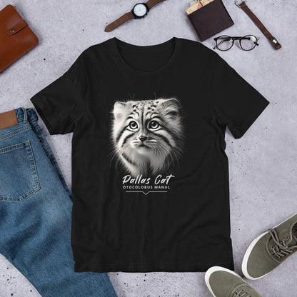 Black t-shirt featuring a close-up, black-and-white illustration of a Pallas kitten's face with striking fur details and intense eyes. Below the image, 'Pallas Cat' is written in elegant white script, followed by 'Otocolobus Manul' in smaller capital letters.