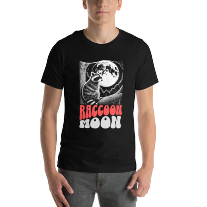 Front view of a model wearing the "Raccoon Moon" t-shirt, highlighting the detailed illustration and text design. The black t-shirt contrasts with the white moon and red lettering, creating a captivating, mystical aesthetic.