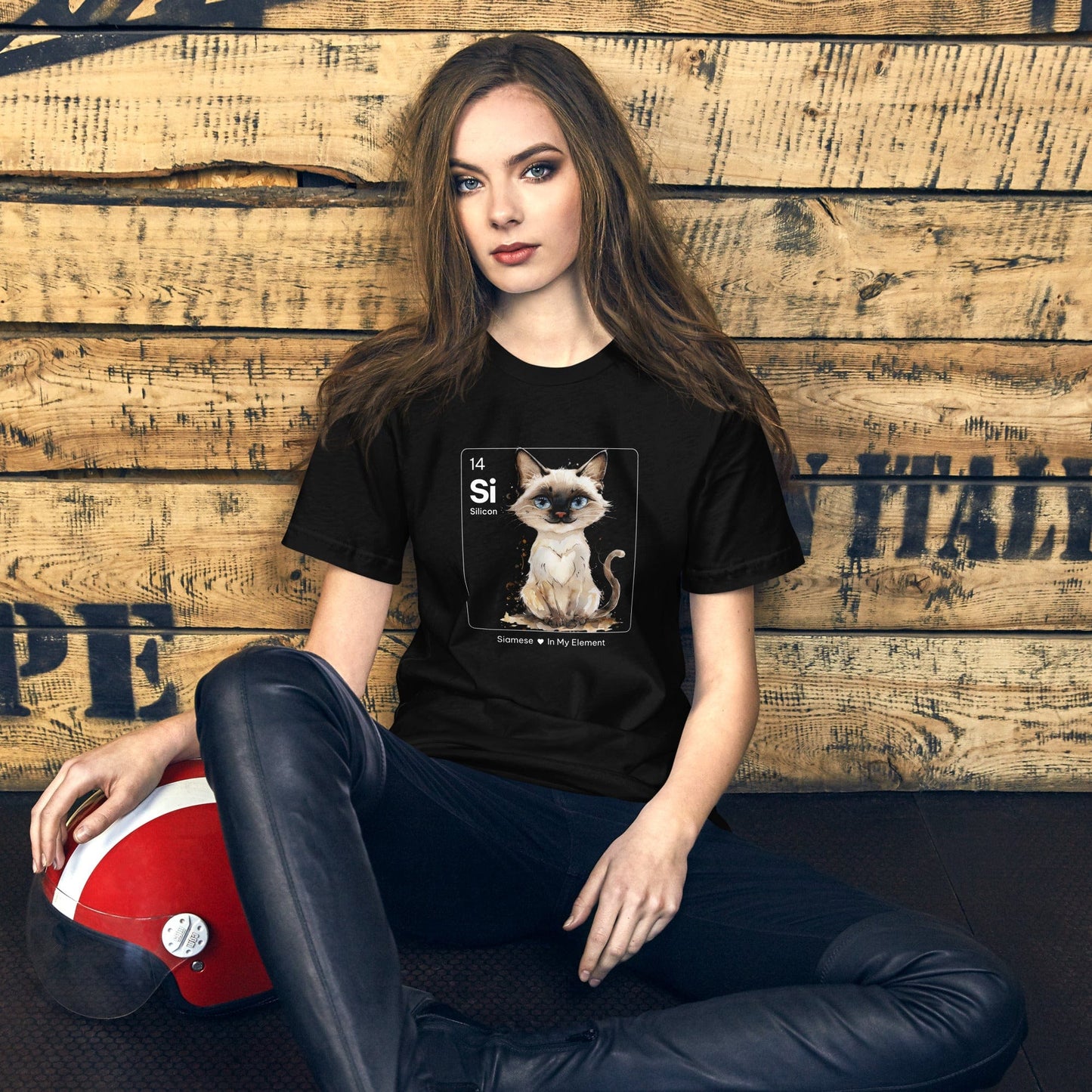 Woman wearing black t-shirt featuring a cute Siamese cat illustration inside a periodic table-inspired square labeled 'Si' for Silicon, with the text 'Siamese In My Element' below.