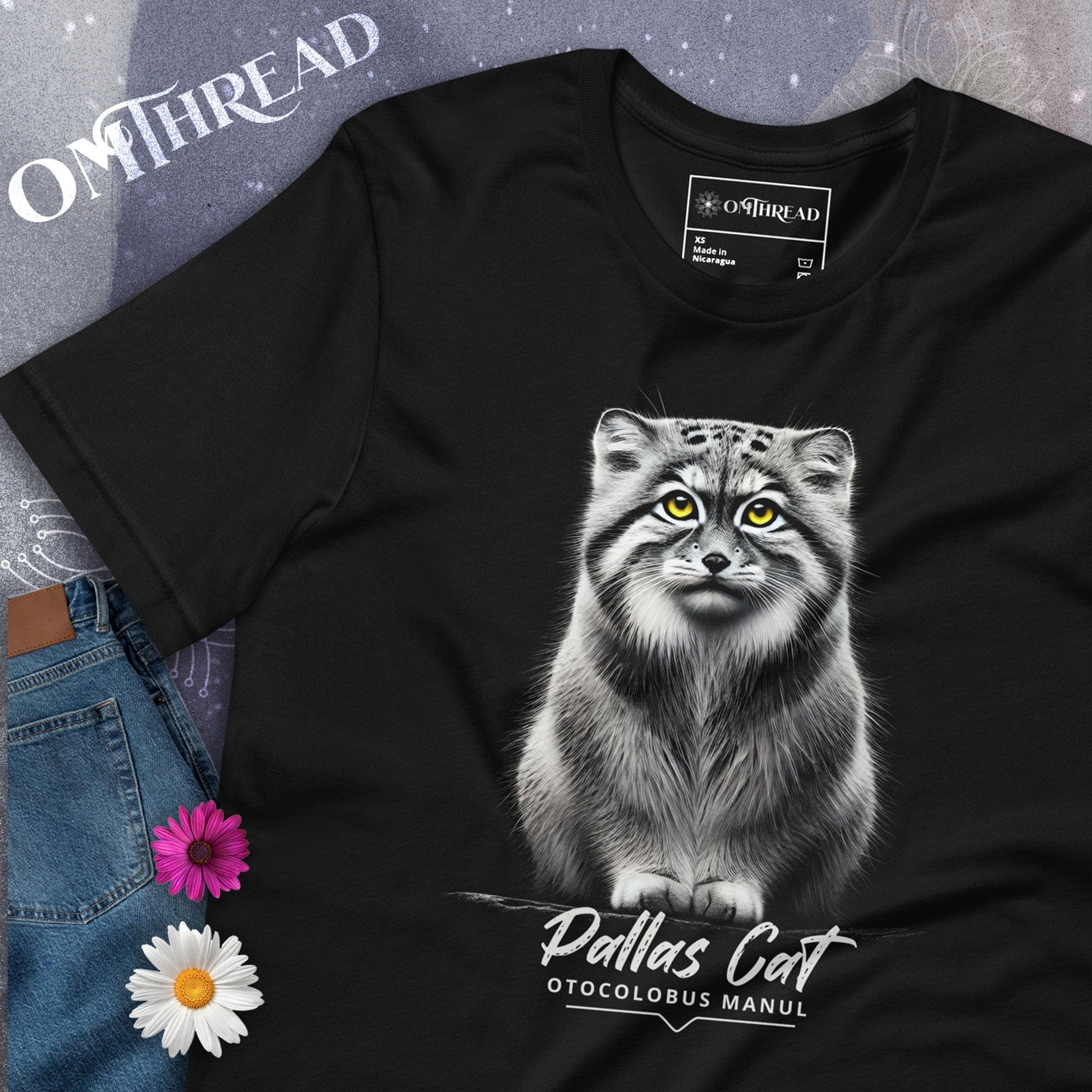 Black t-shirt featuring a realistic illustration of a Pallas cat with bright yellow eyes, sitting calmly. Below the cat, the text reads 'Pallas Cat' and 'Otocolobus Manul' in an elegant font.