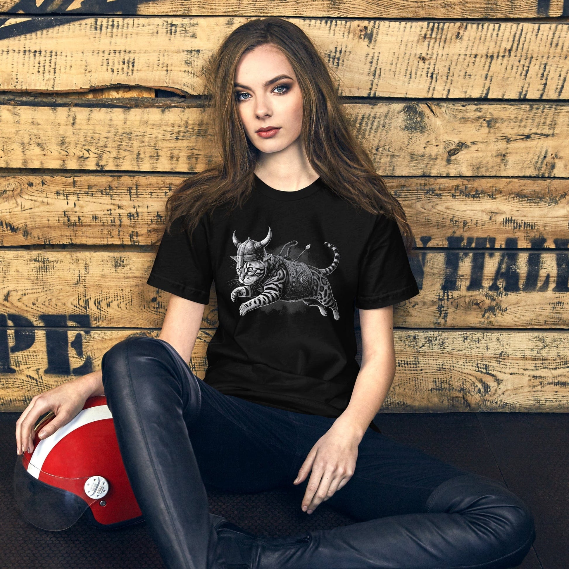 Female model wearing a black t-shirt featuring an illustration of a fierce Bengal cat dressed as a Viking warrior, complete with a horned helmet, armor, and weapons, leaping into action. 